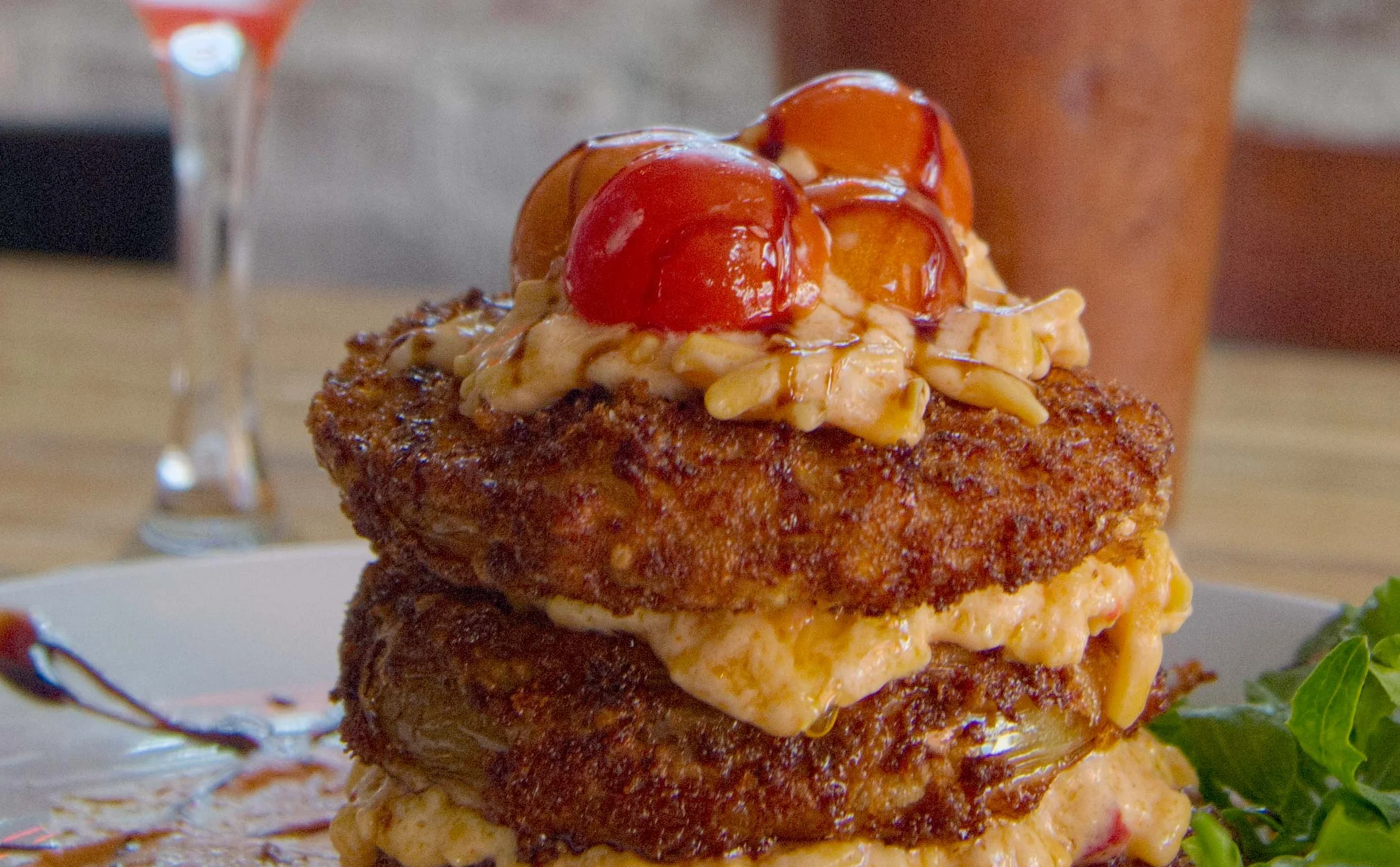 Stacked savory fritters with sauce in a cozy restaurant setting