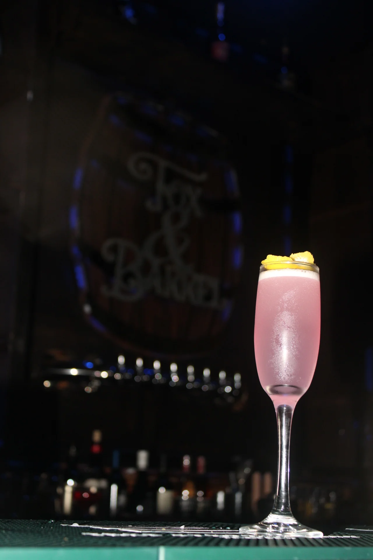 Elegant pink cocktail garnished with lemon slices at a stylish bar