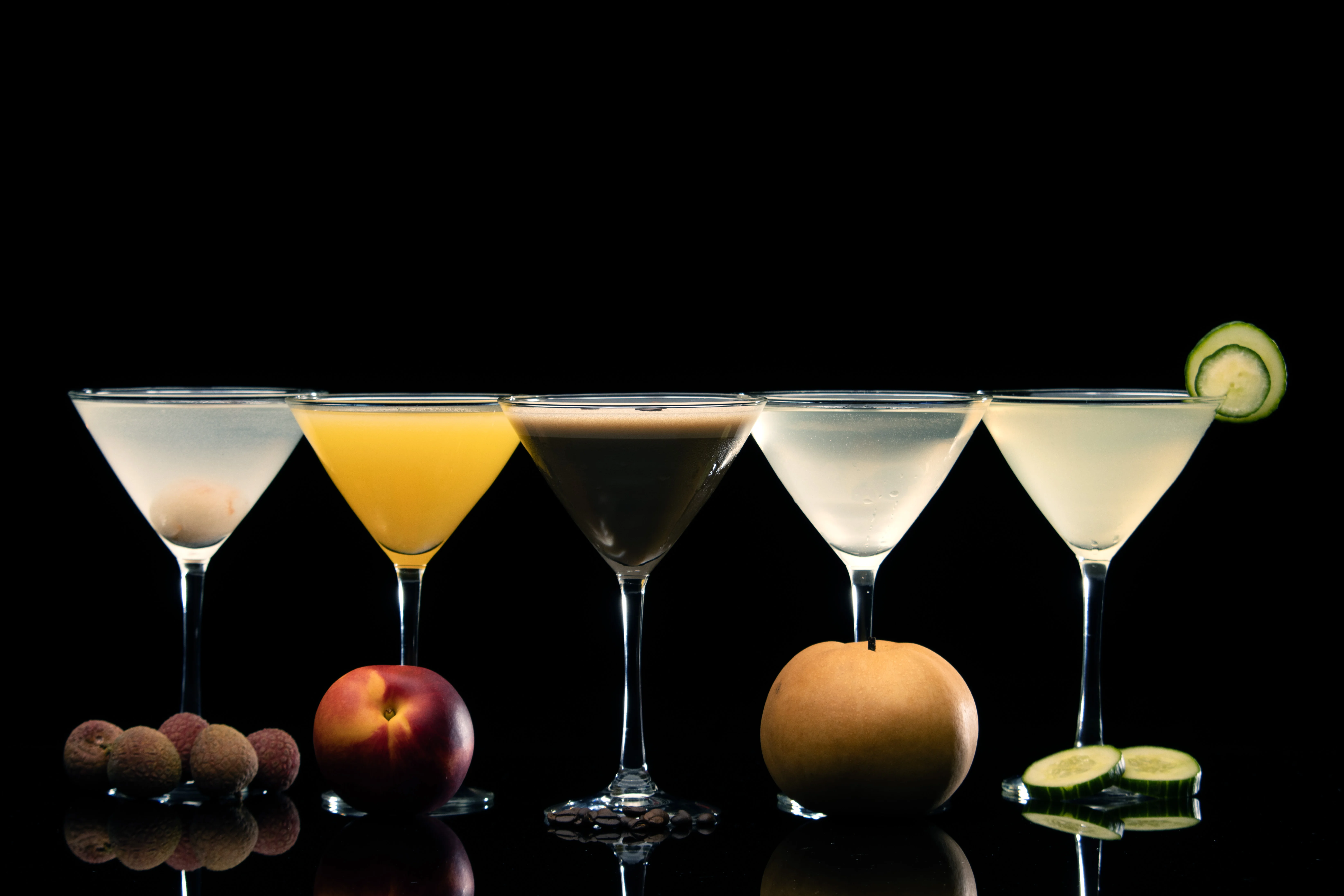 Colorful cocktails lined up on a bar with fresh fruit garnishes