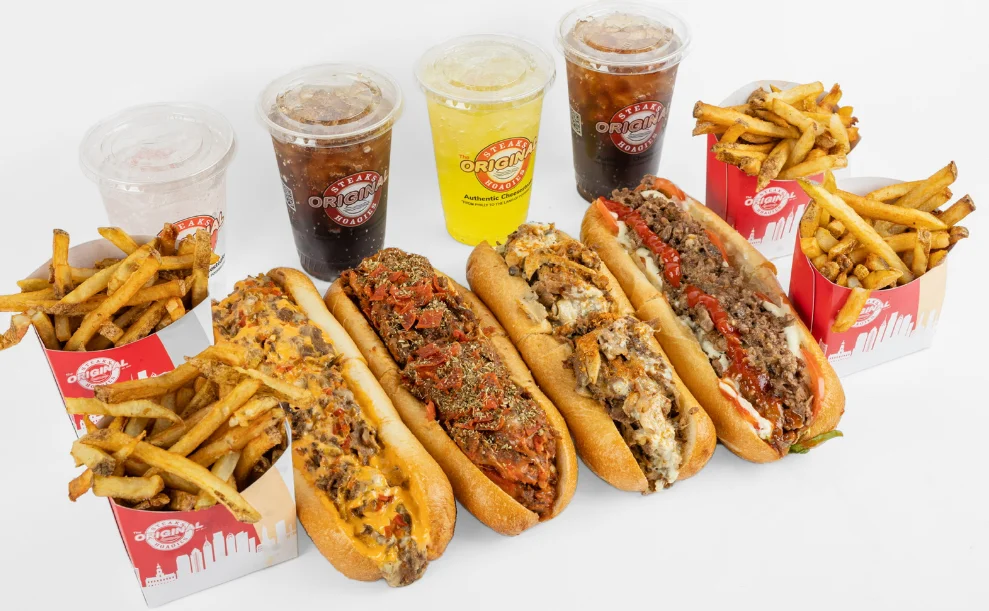 Assorted cheesesteaks with fries and drinks from a classic deli