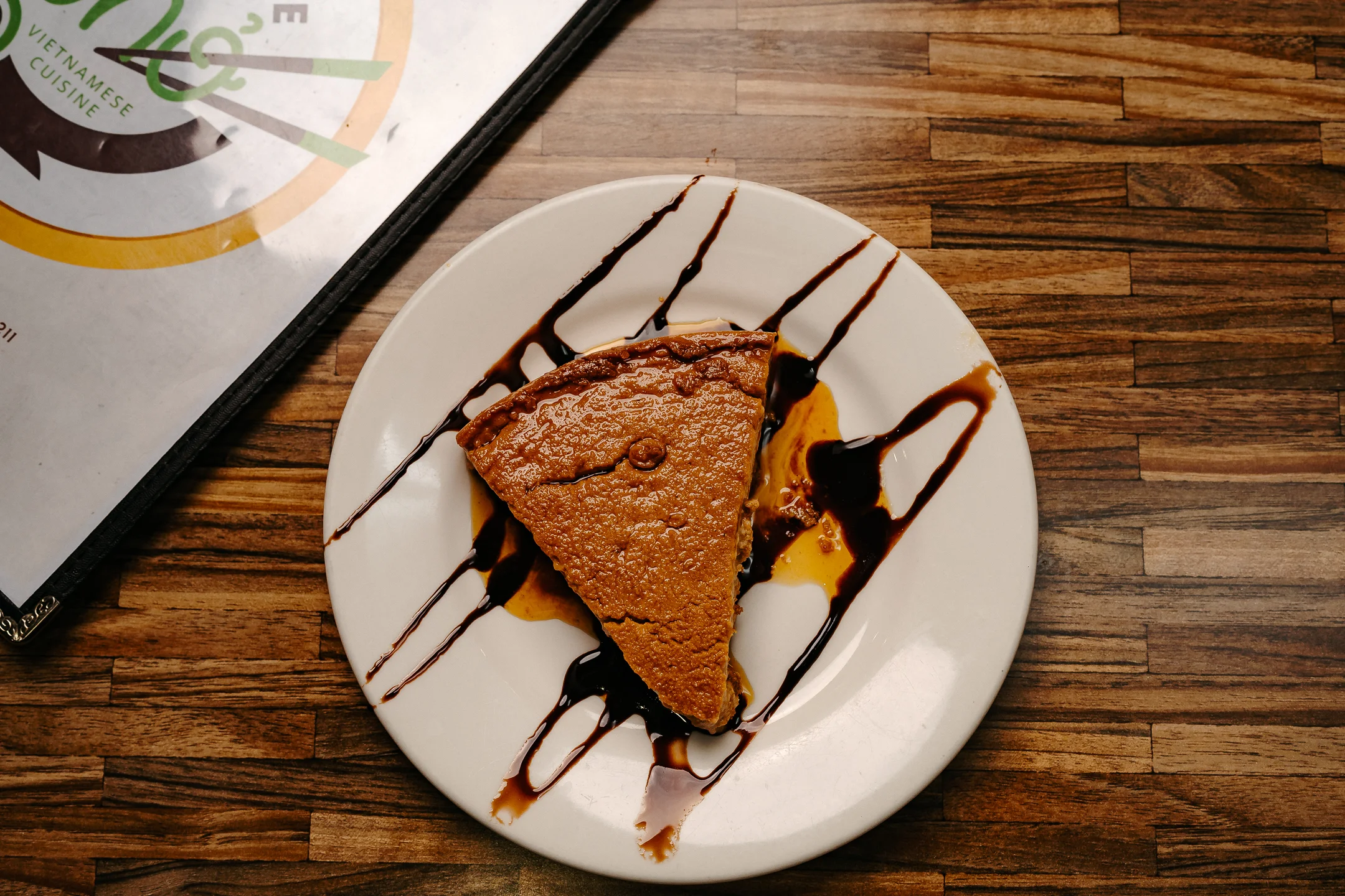 Slice of Vietnamese pumpkin pie drizzled with chocolate sauce