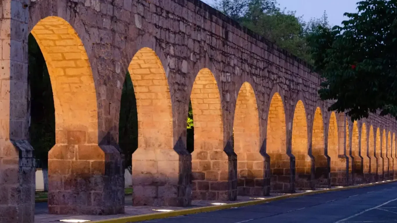 Historic stone aqueduct with illuminated arches at dusk