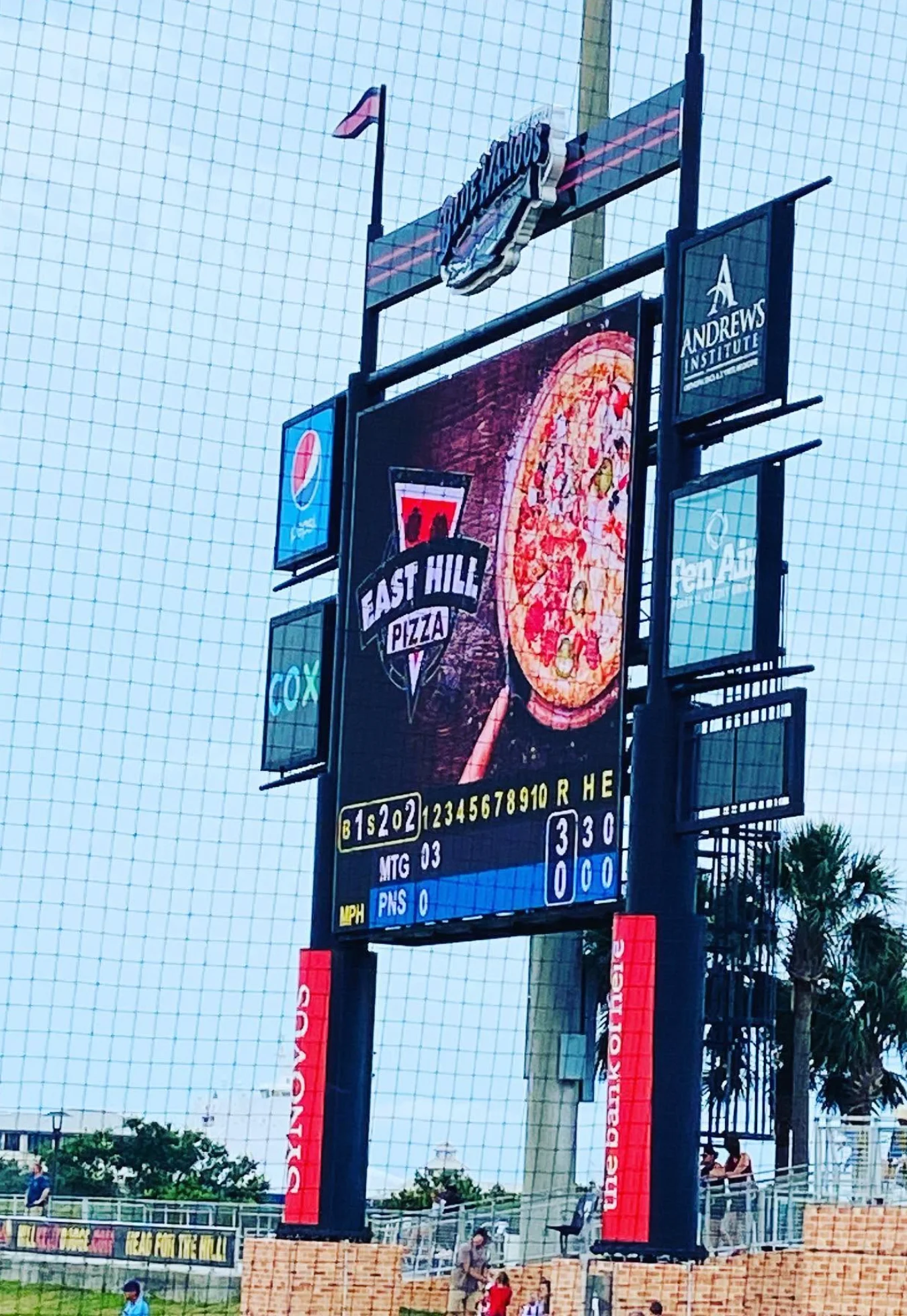 East Hill Pizza billboard and restaurant signage outside a sports venue