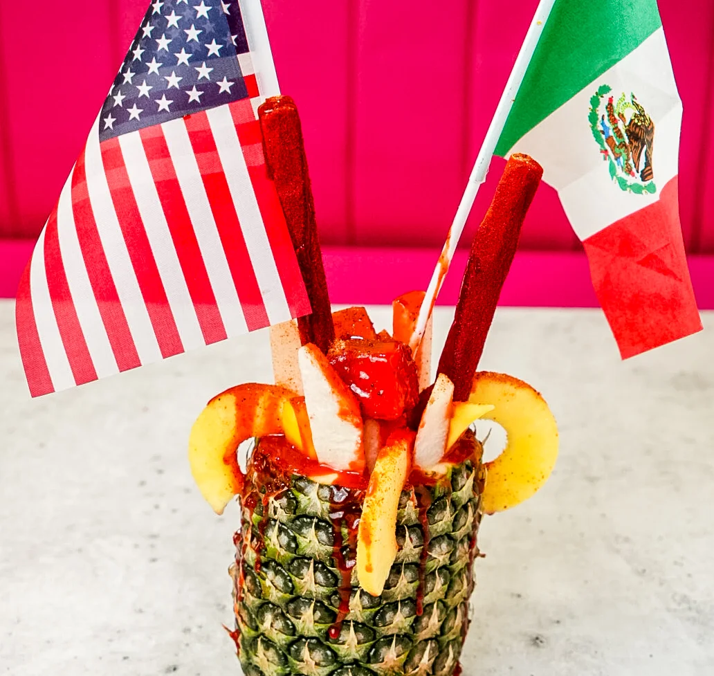 Colorful Mexican michelada in a clay mug with garnishes
