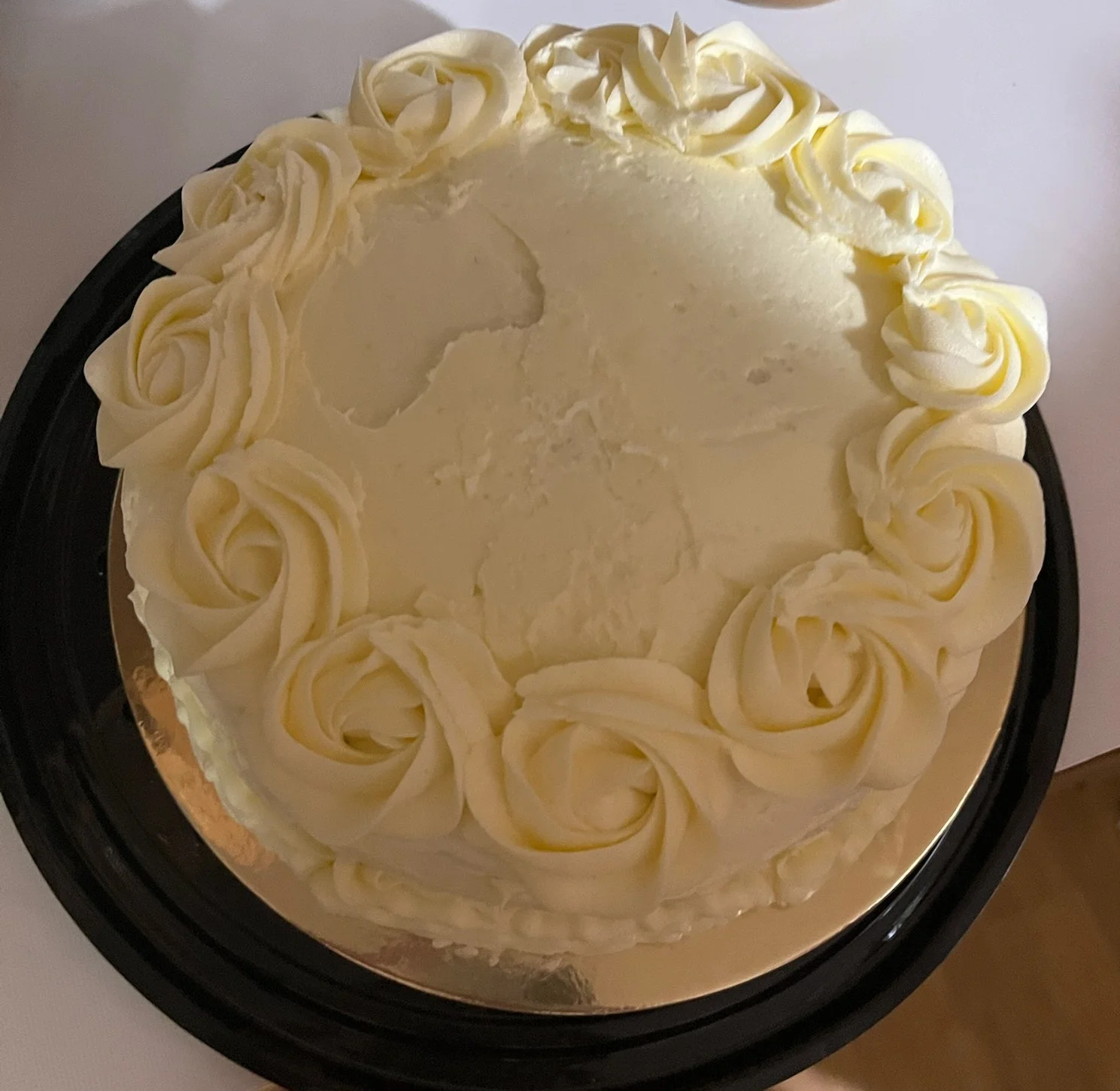 A round cake decorated with piped frosting roses on the edge.