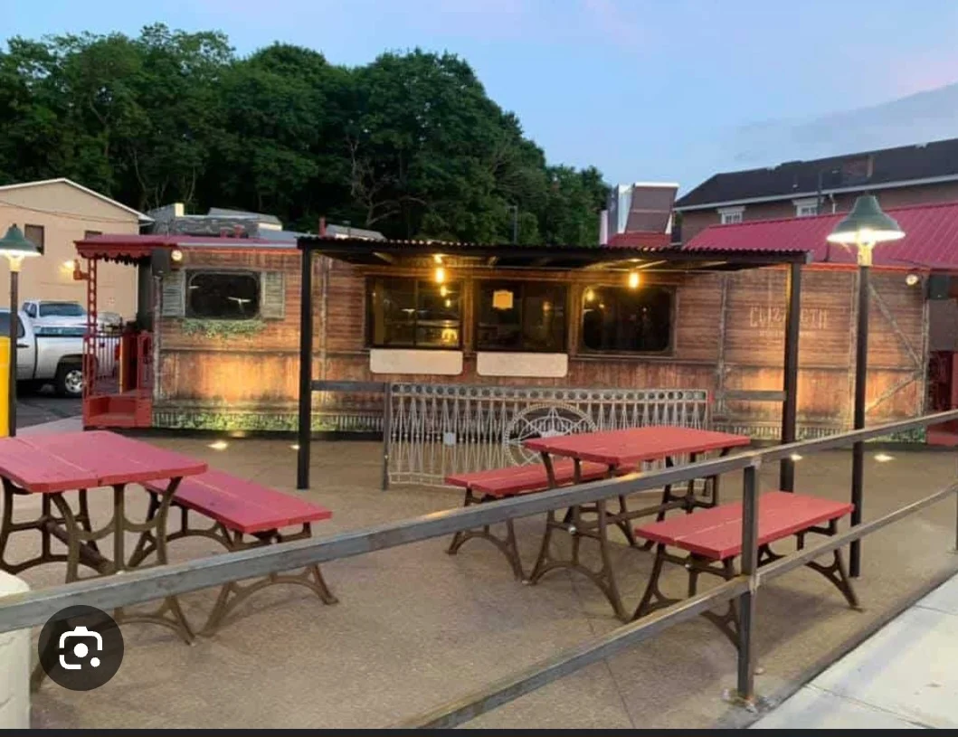 Outdoor dining area with rustic food truck and picnic tables