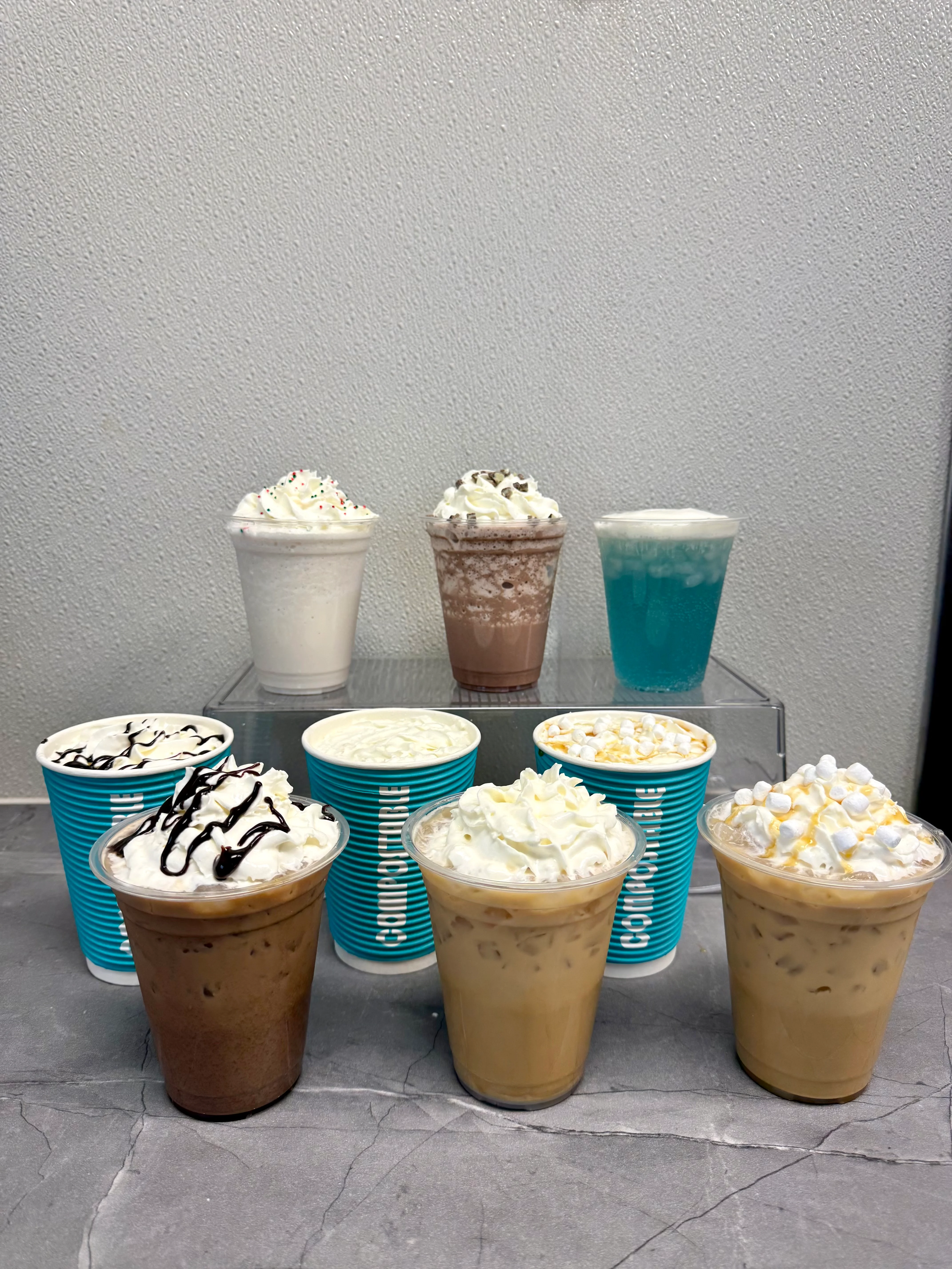 Colorful assortment of iced beverages with whipped cream toppings