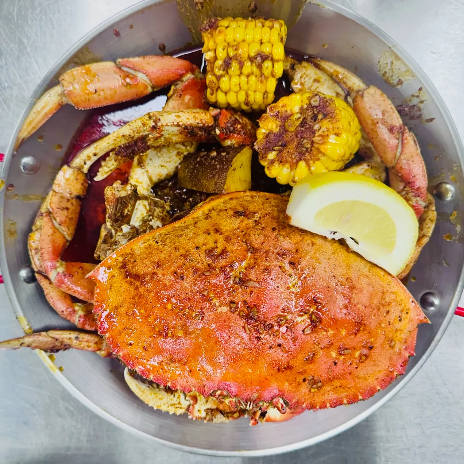 A pot filled with crab, corn, and lemon, showcasing a seafood feast.