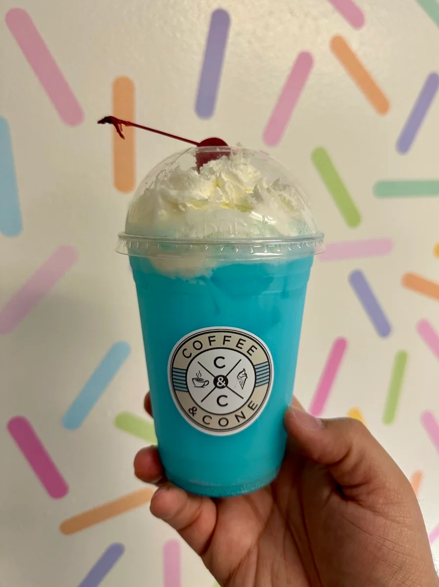 Vibrant blue slush drink topped with whipped cream and a cherry