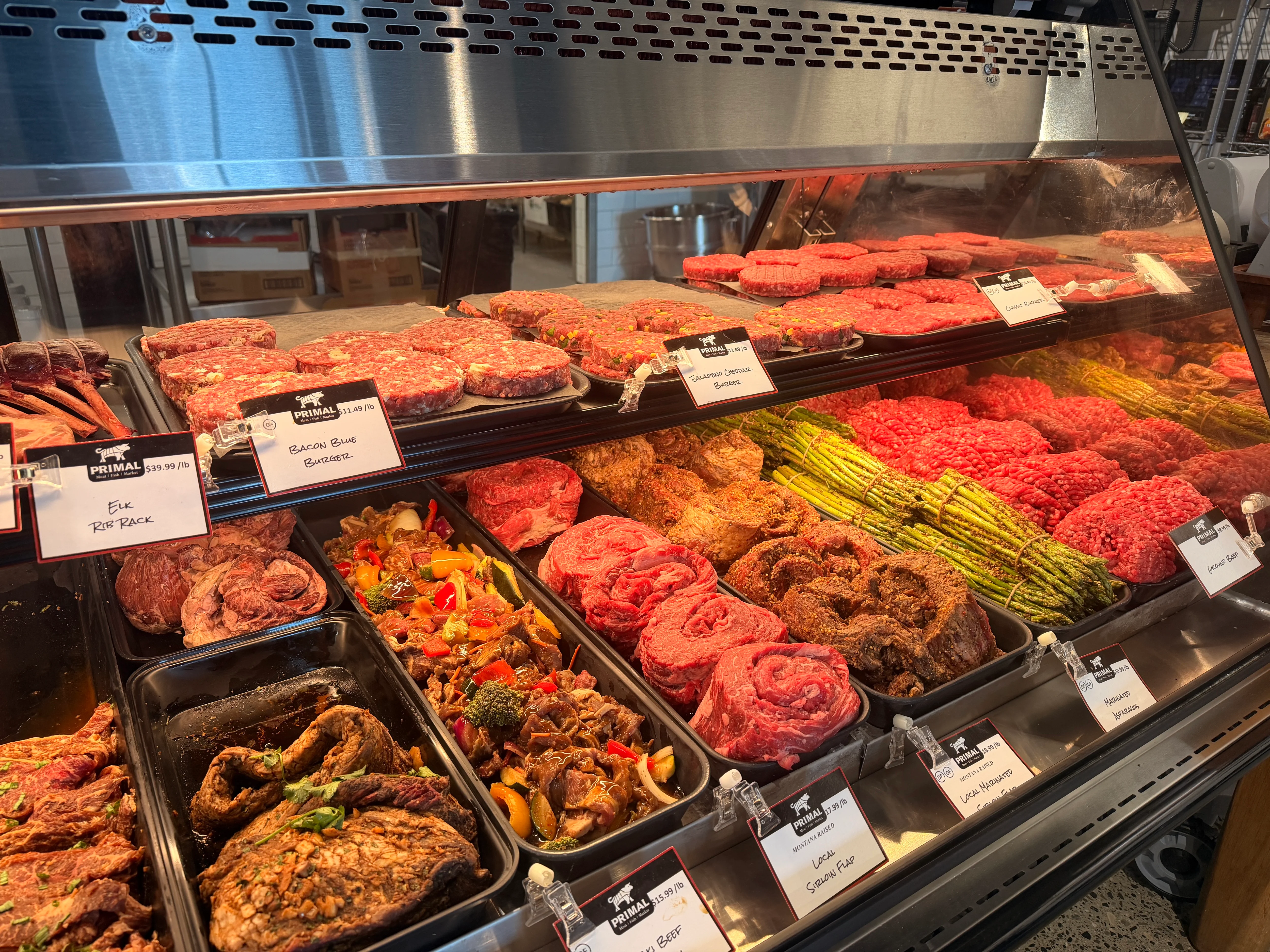 Display case of fresh gourmet beef cuts and seasoned burgers