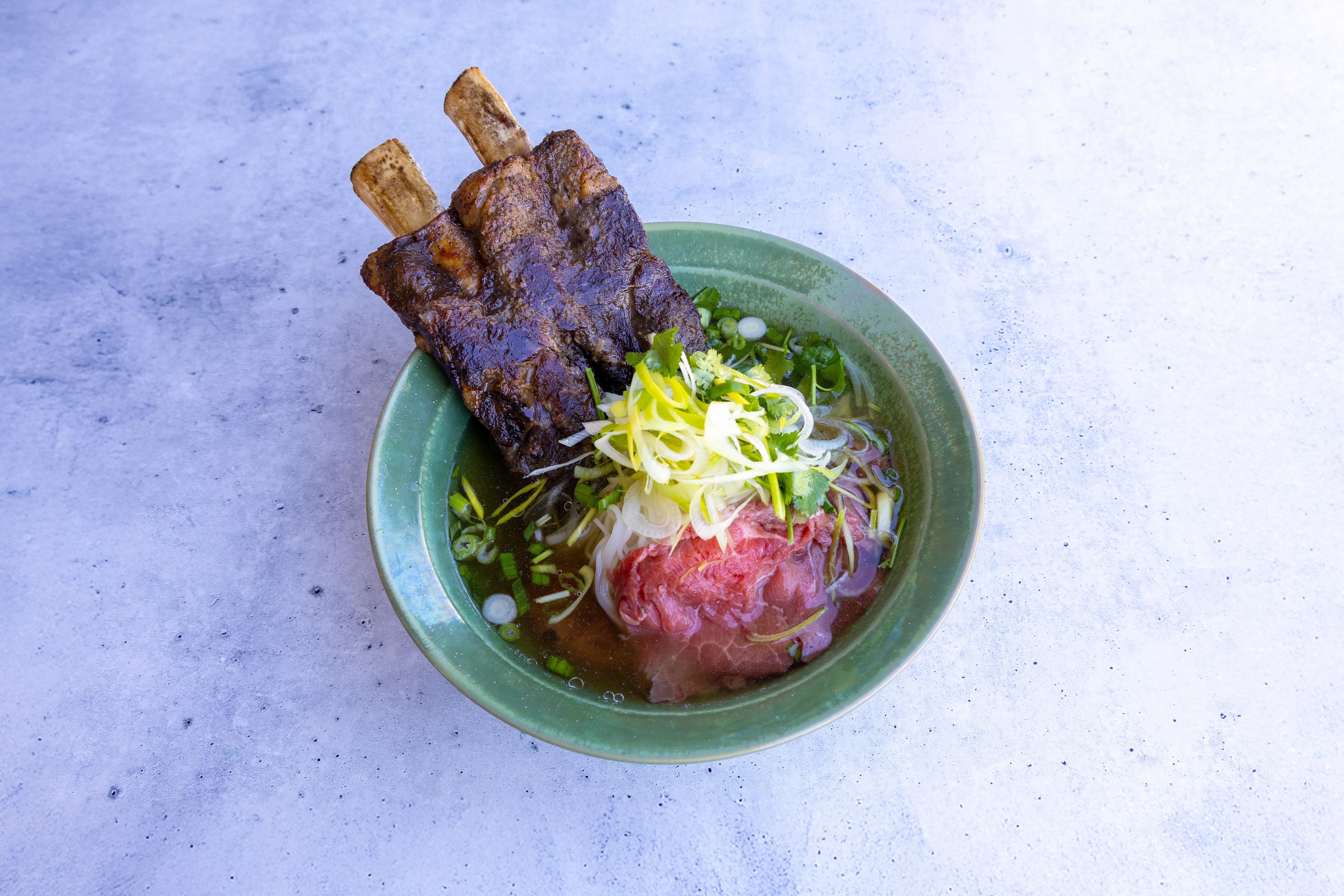 Bowl of Vietnamese pho with beef short ribs and fresh herbs