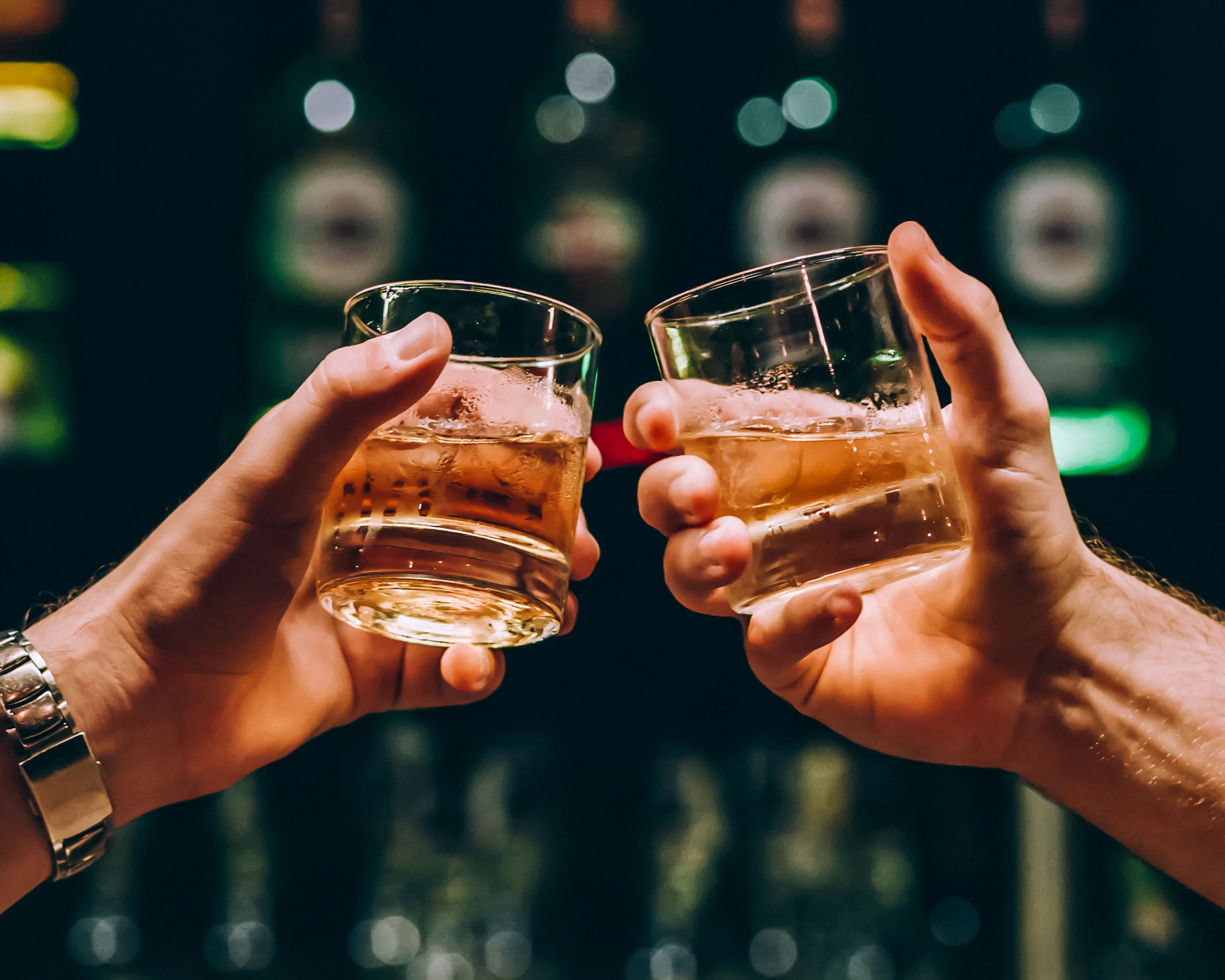 Cheers with whiskey cocktails in a bar setting
