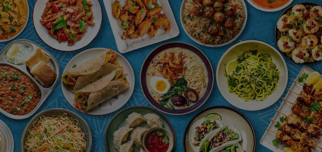 Assorted global dishes including pasta, tacos, and dumplings on a vibrant table