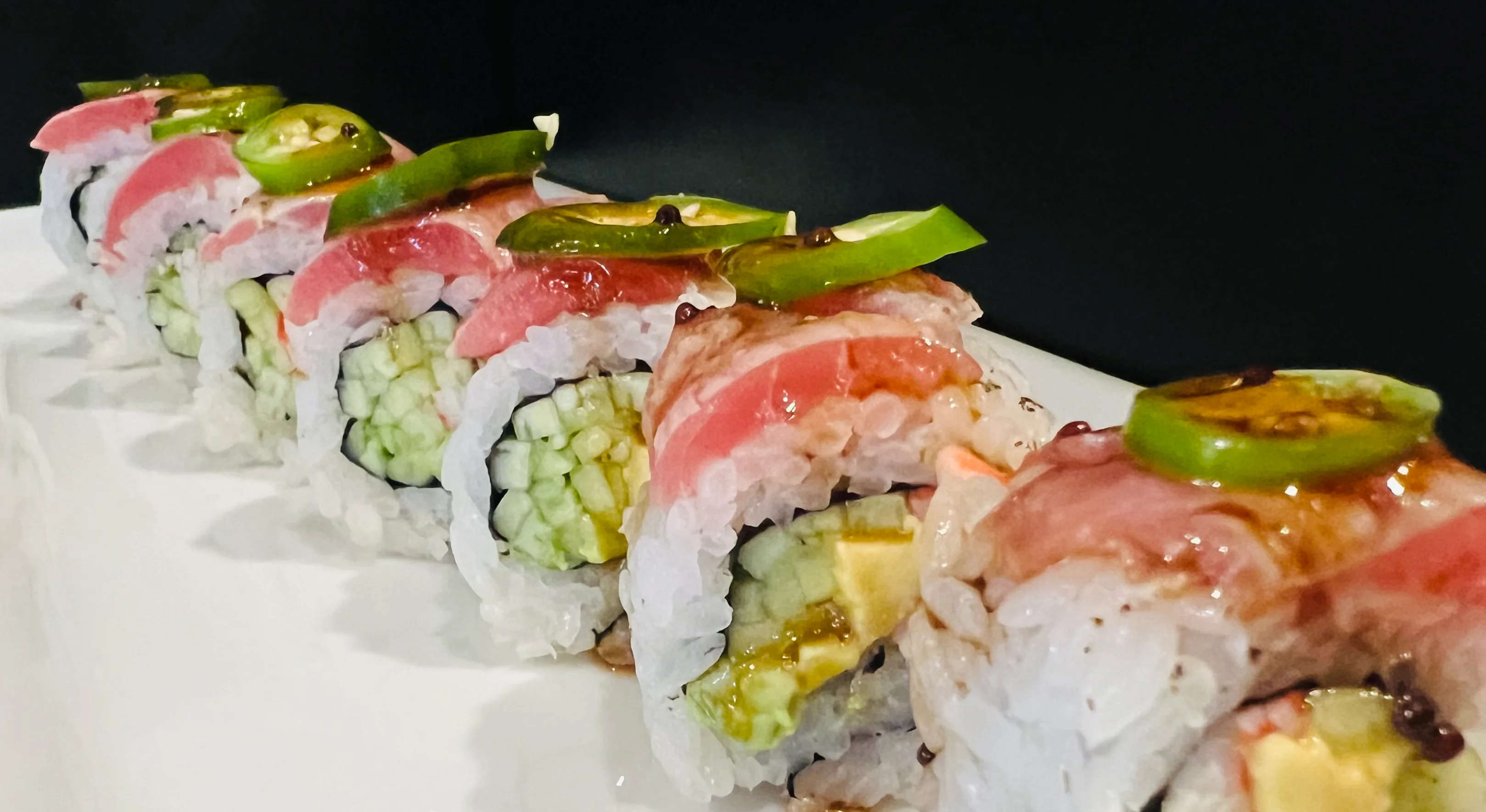 A beautifully arranged Tuna Tataki Roll with vibrant colors and garnishes.