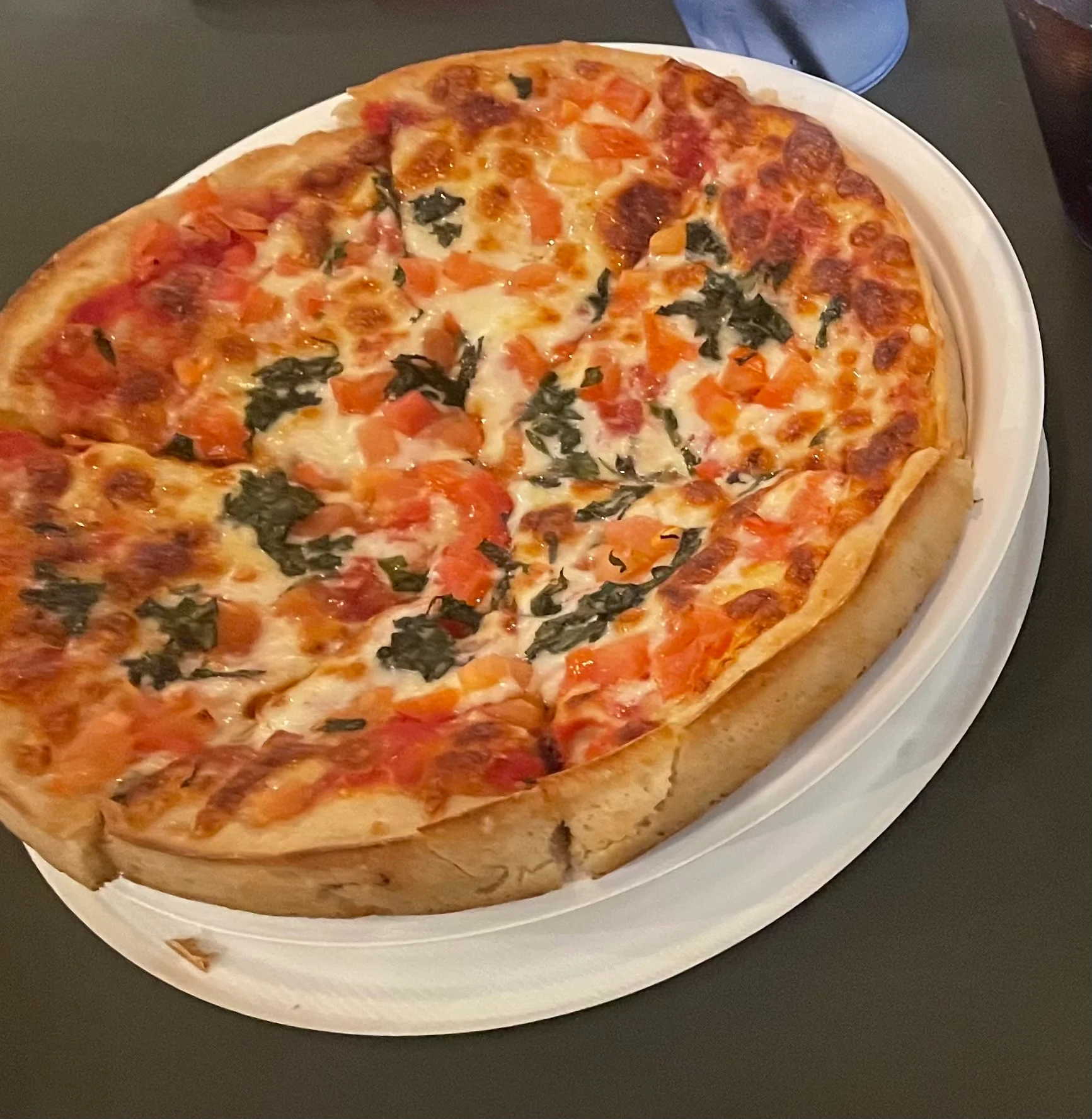 Deep-dish pizza topped with fresh tomatoes and spinach