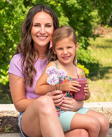 Mother and daughter enjoying a sunny day with flowers and a smoothie