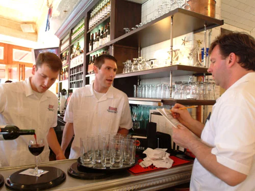 Bartenders collaborating at a stylish bar counter with wine and glasses