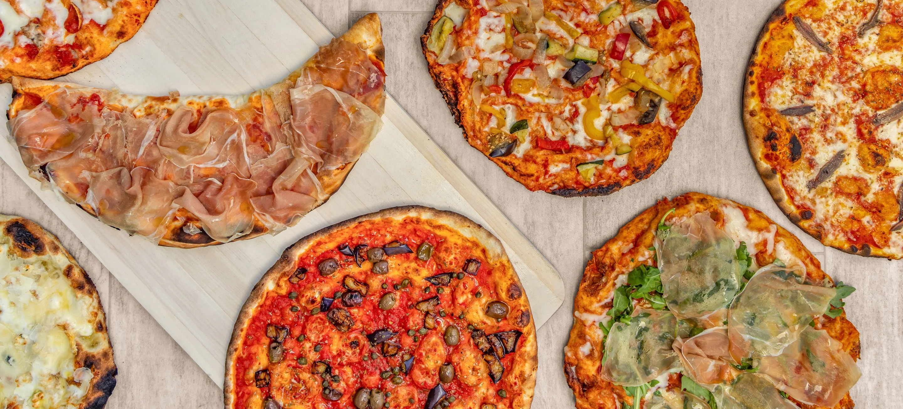 Variety of gourmet pizzas on a wooden board