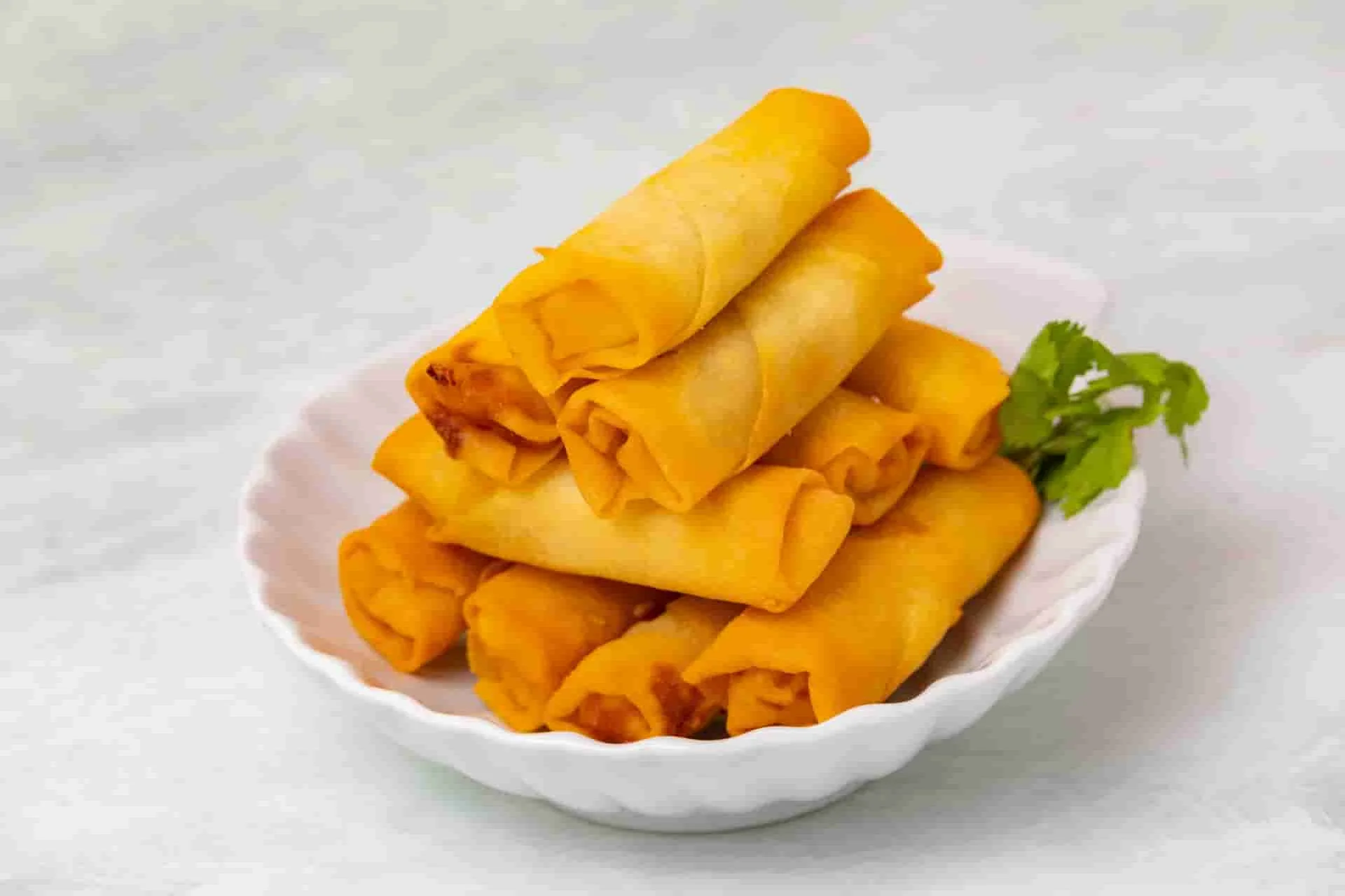 Crispy golden spring rolls served with cilantro