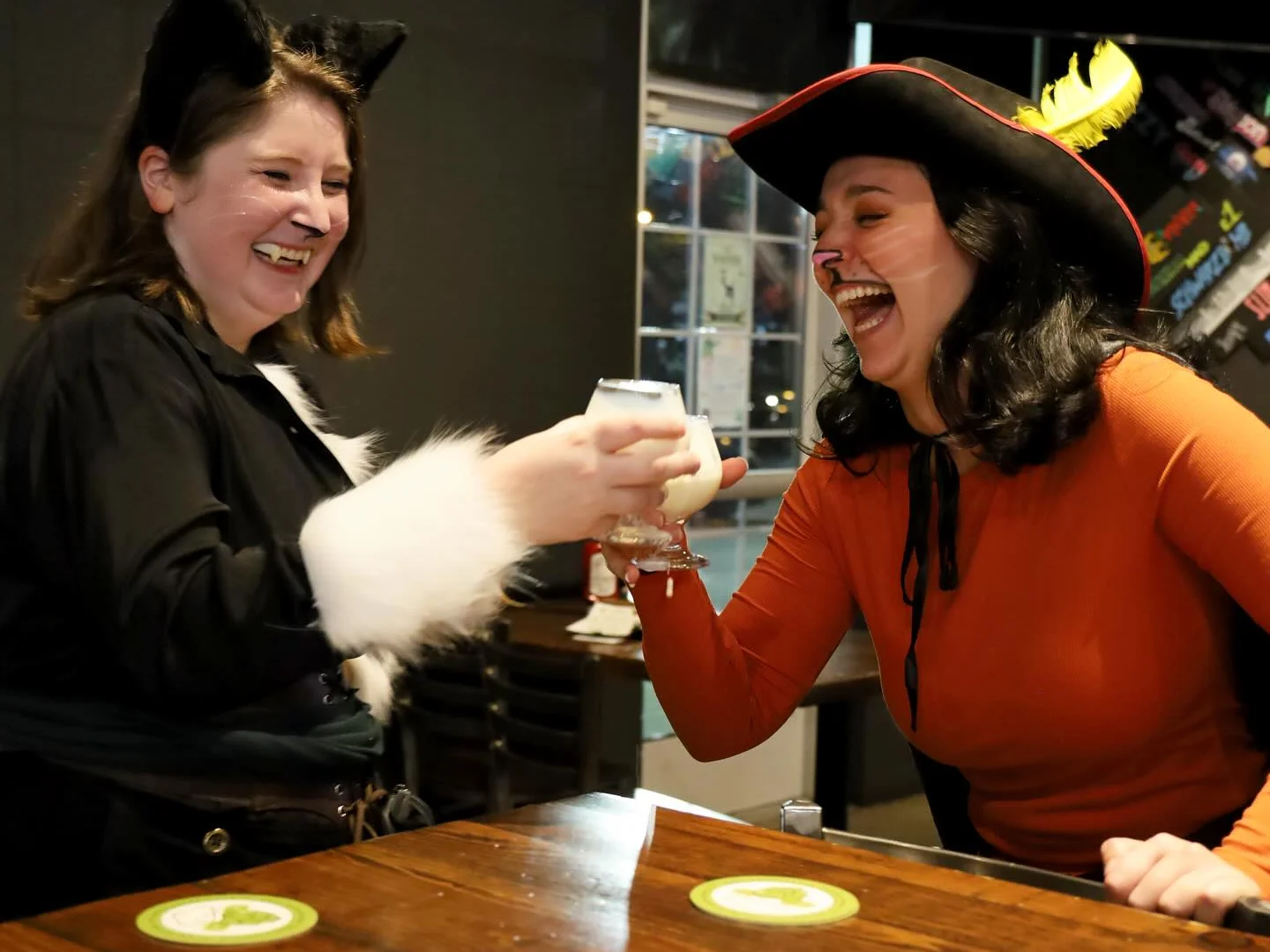 Two friends celebrating with drinks in a festive bar setting