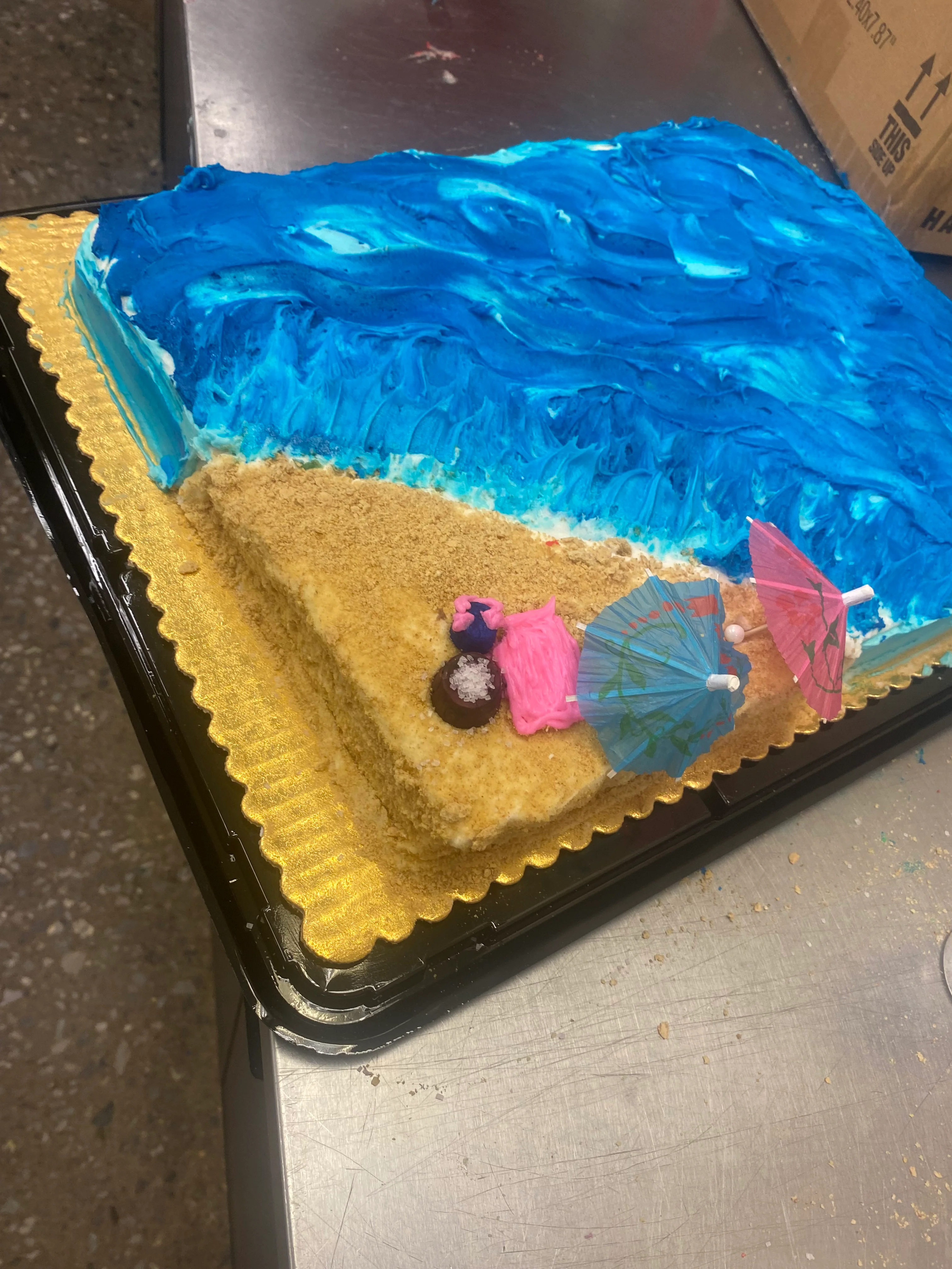 Colorful beach-themed cake with blue frosting and decorative umbrellas