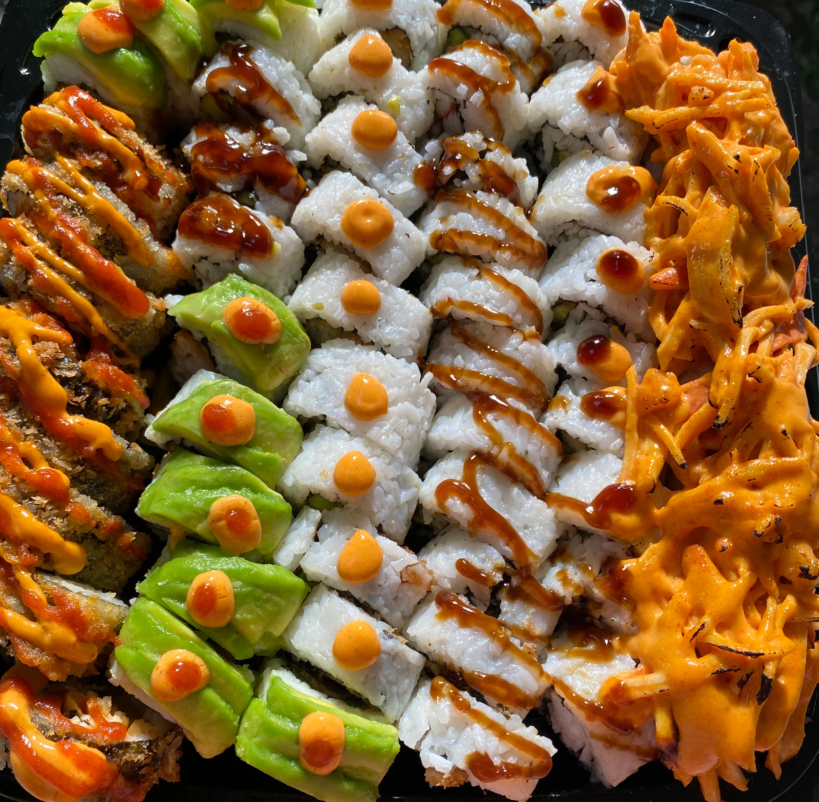 Colorful plantain sushi rolls with fresh vegetables and sauces.