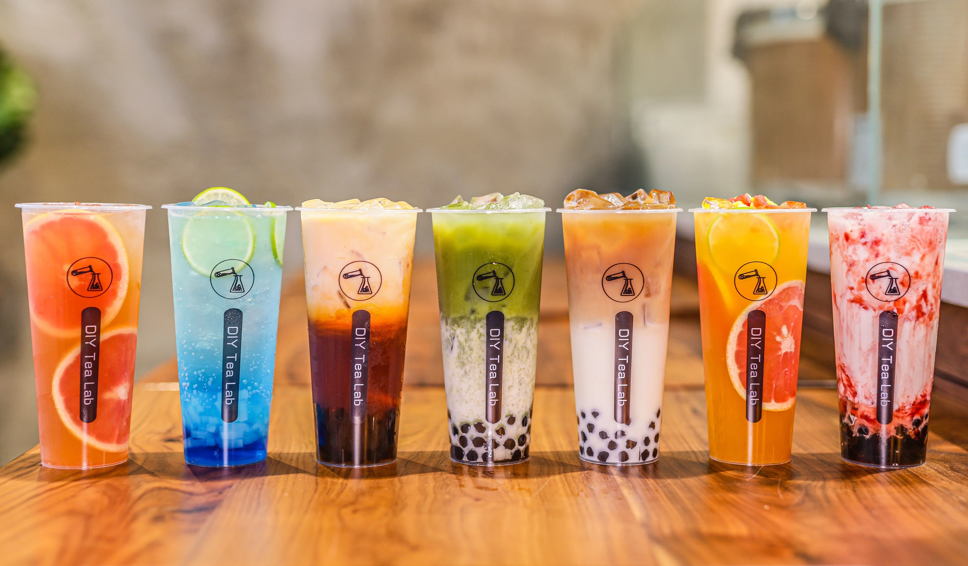 Colorful bubble tea drinks in clear cups on a wooden table