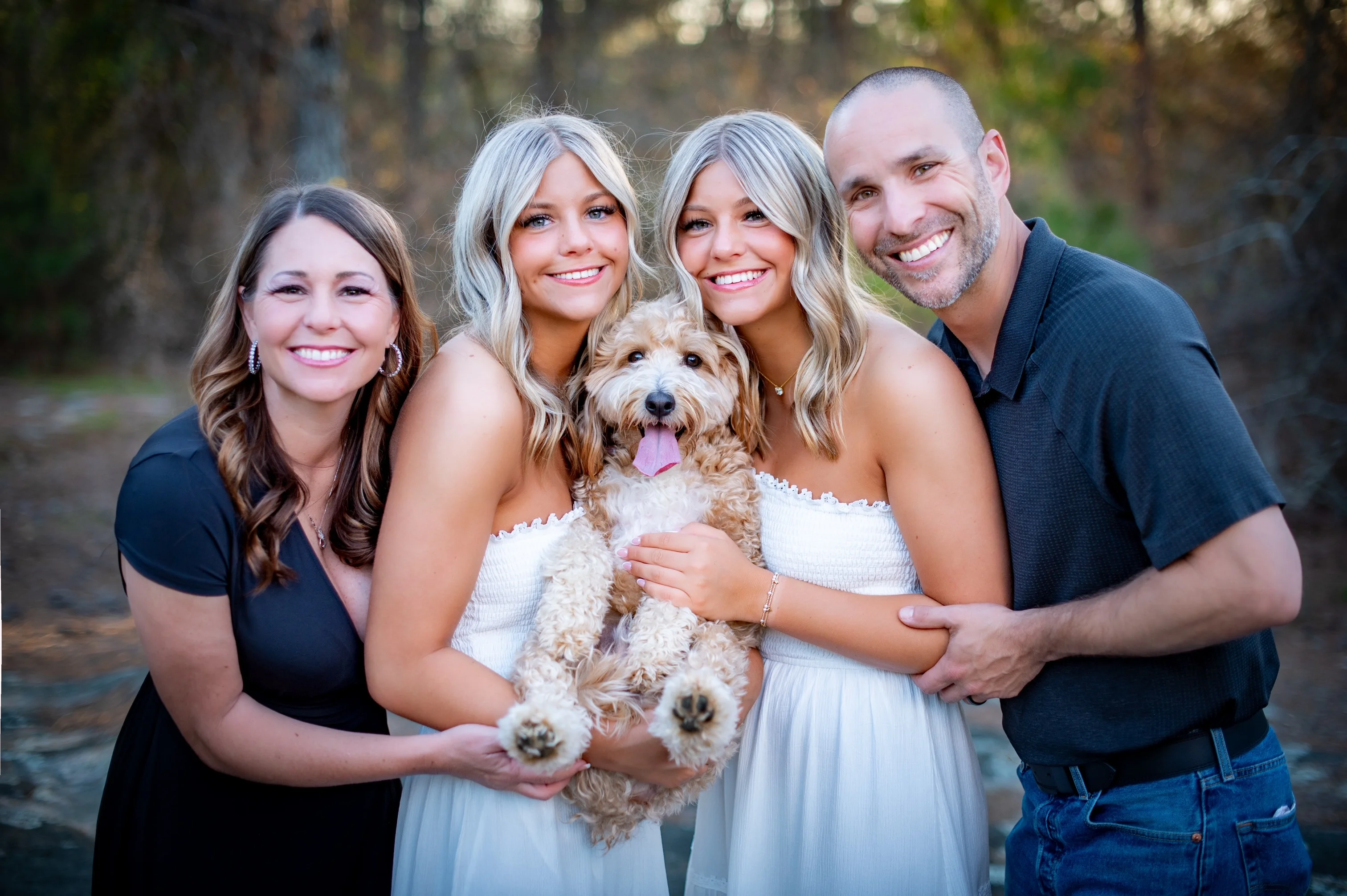 Family portrait with two women, a man, and a dog in a natural setting