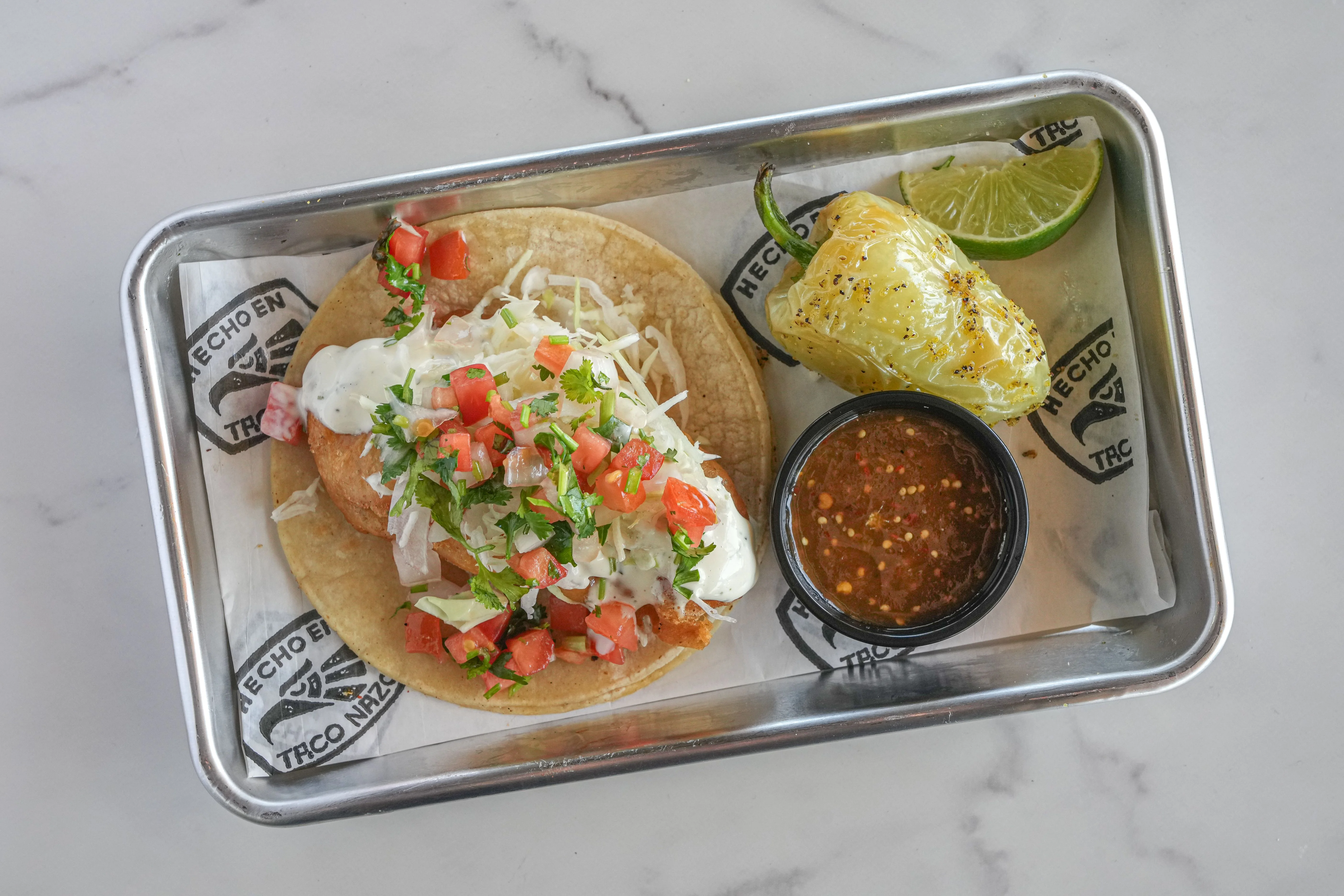 Plated fish taco with salsa and chile