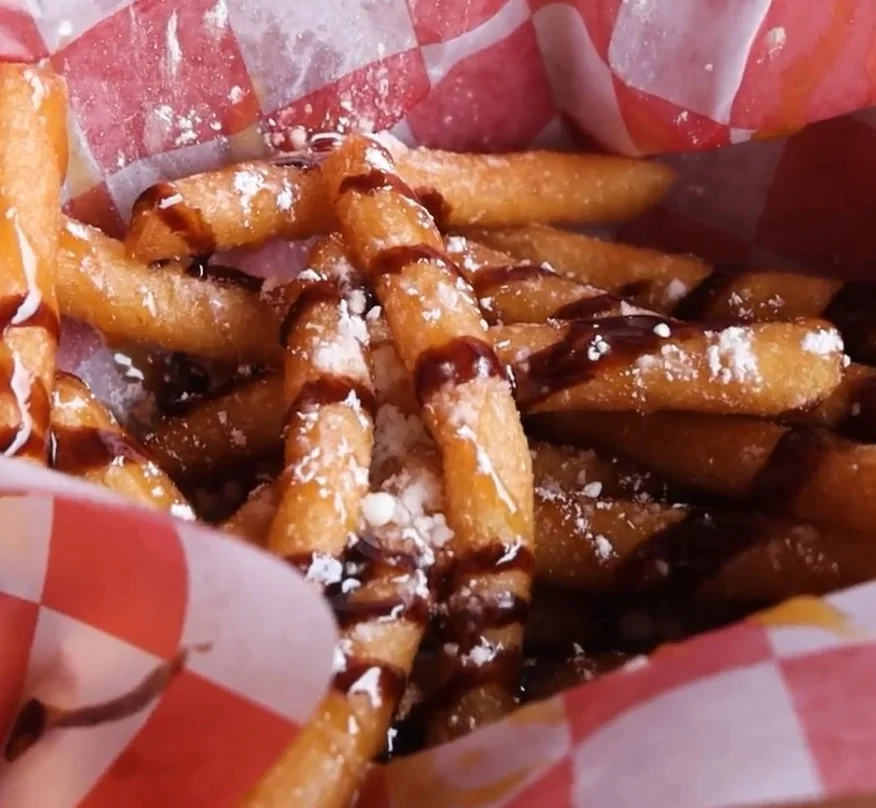 Funnel cake fries drizzled with chocolate and powdered sugar