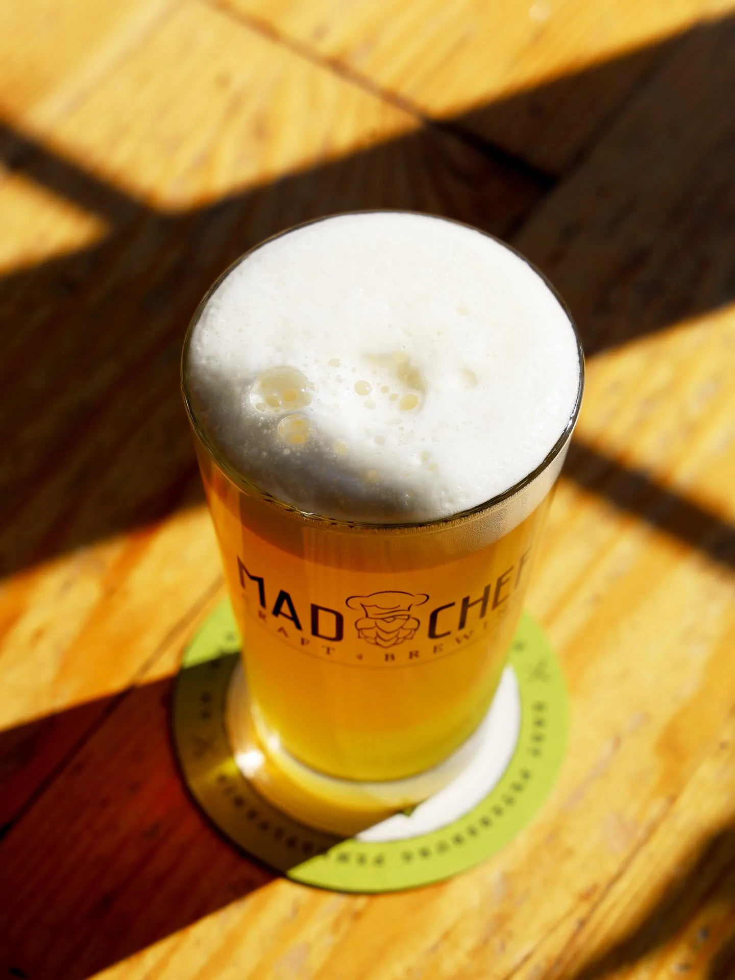Craft beer in a glass with frothy head on a wooden table