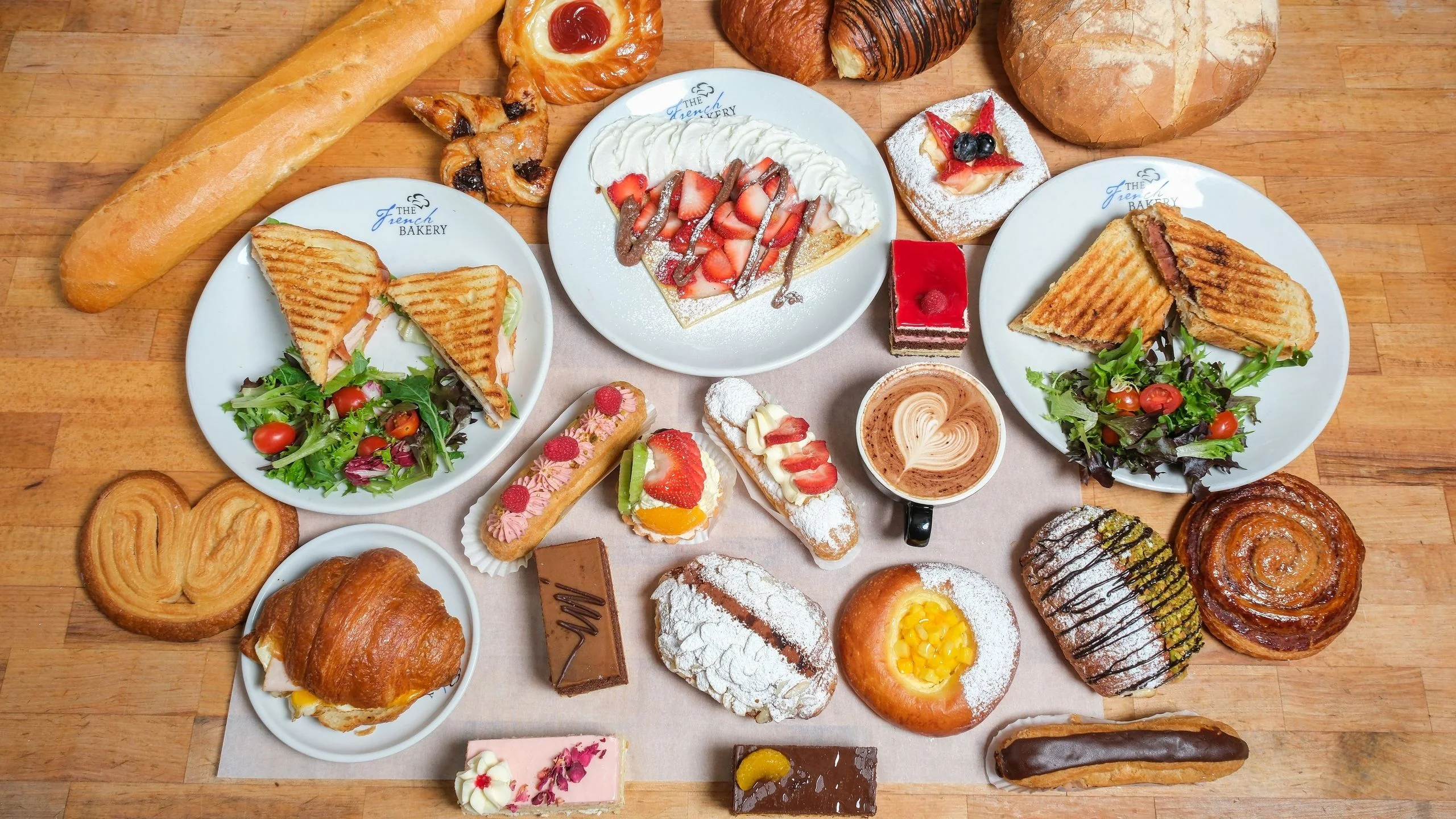 Assorted French pastries and sandwiches on a wooden table
