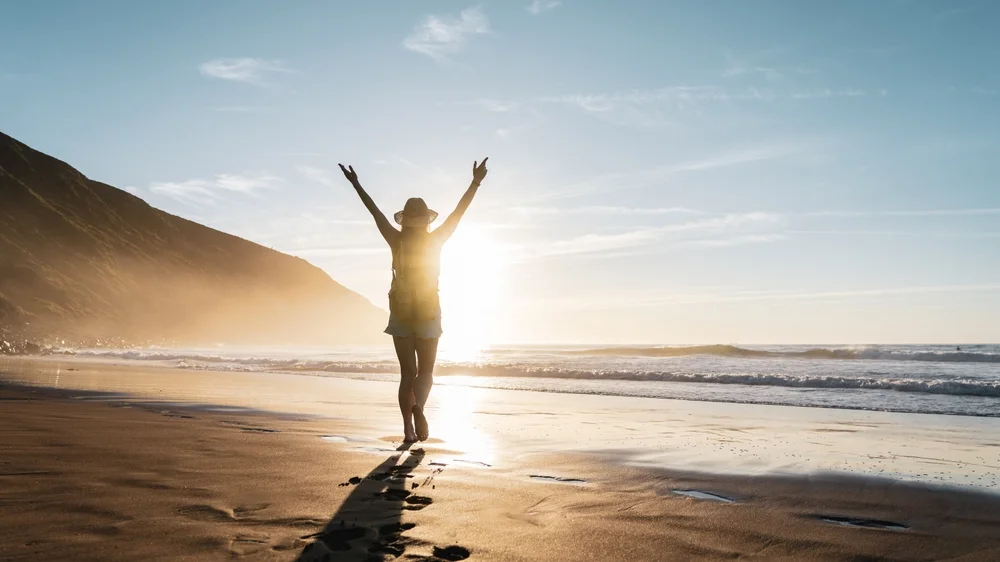 Person celebrating on a beach at sunset