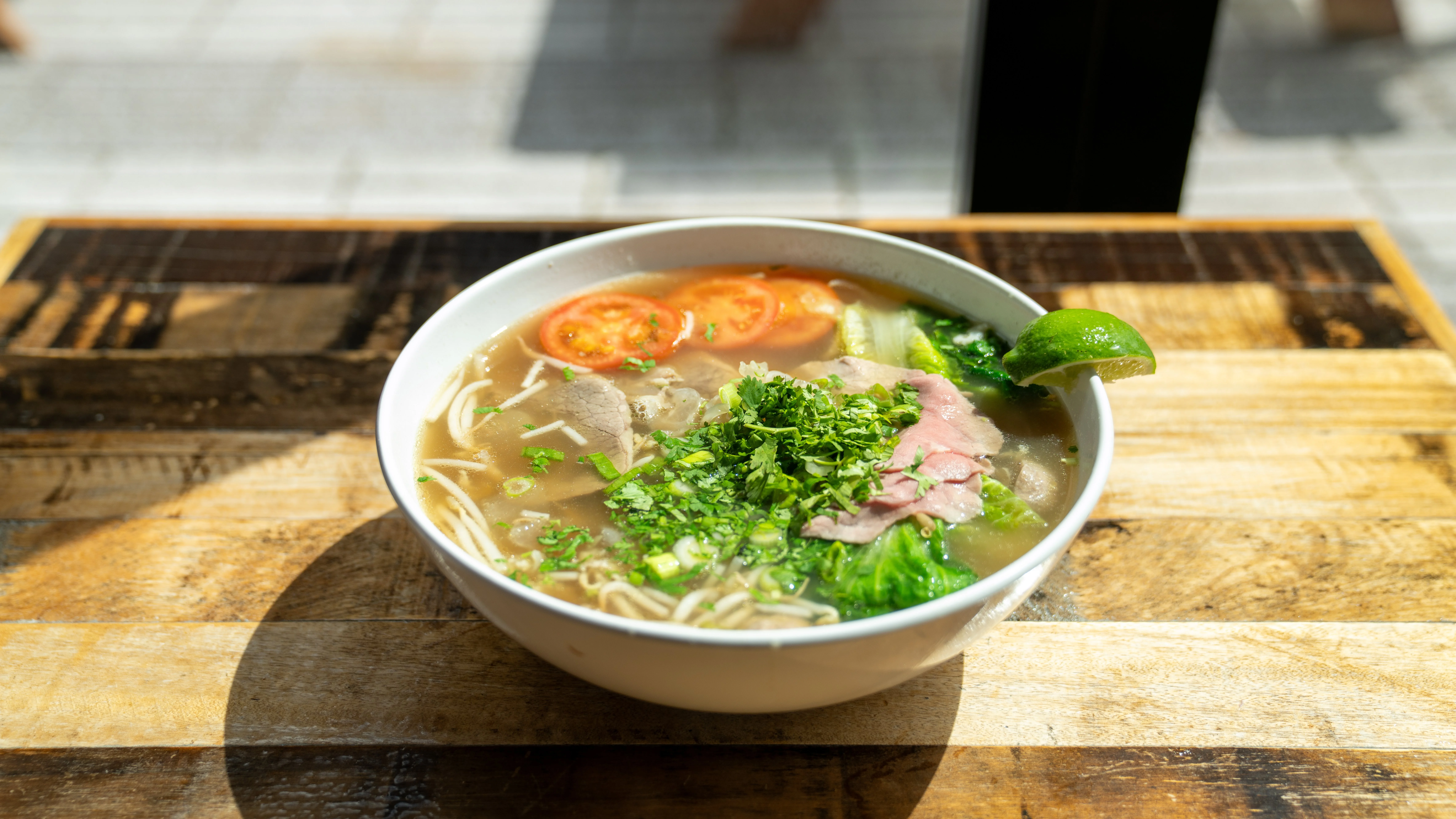 Bowl of Vietnamese pho with fresh herbs and lime