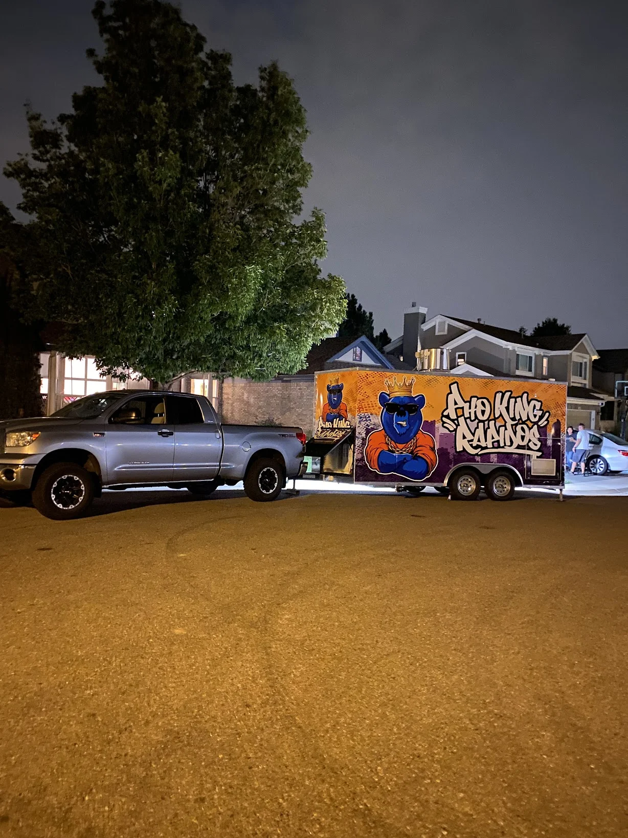 Food truck with vibrant graffiti art parked on a street at night