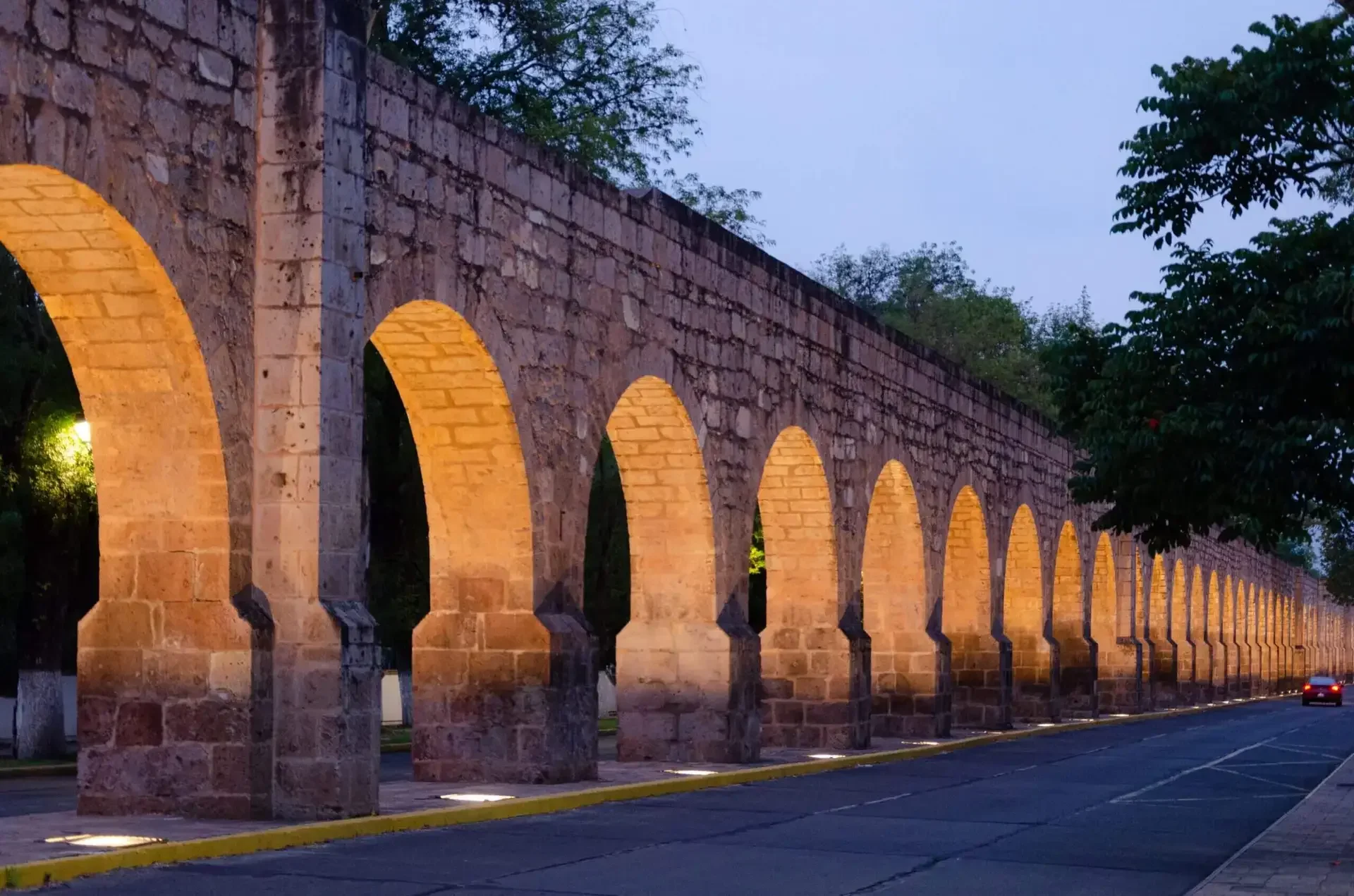 Historic stone aqueduct with illuminated arches at dusk