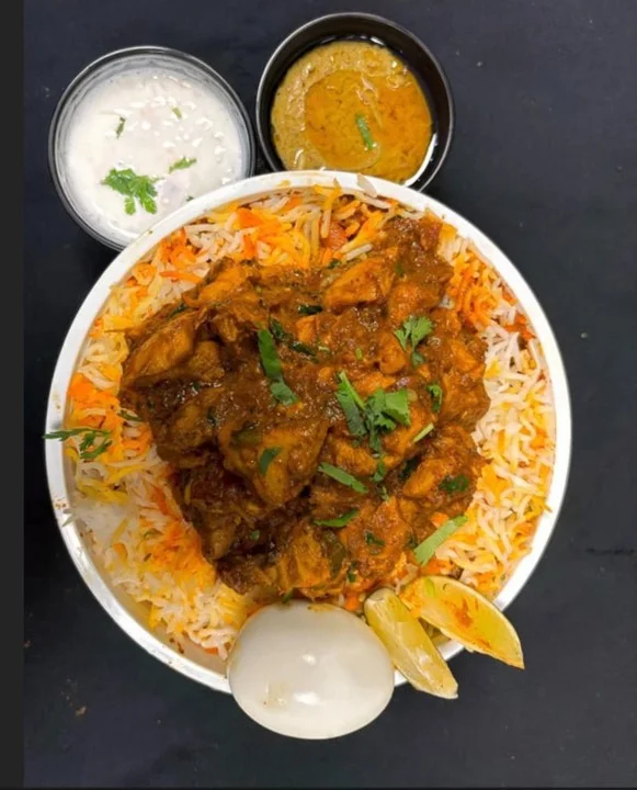 Flavorful chicken biryani served with raita and chutney