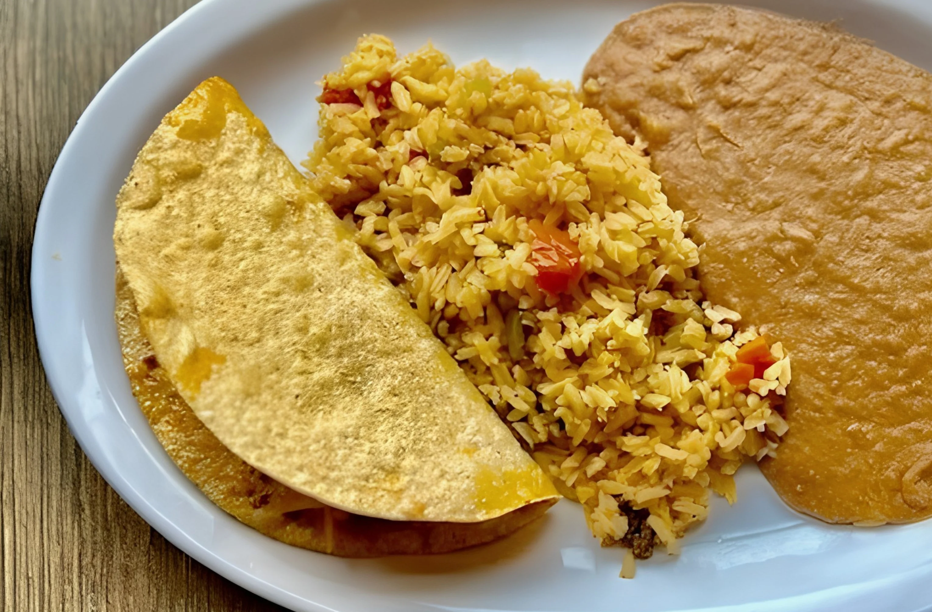 Plate with rice, a taco, and a side of bean sauce.