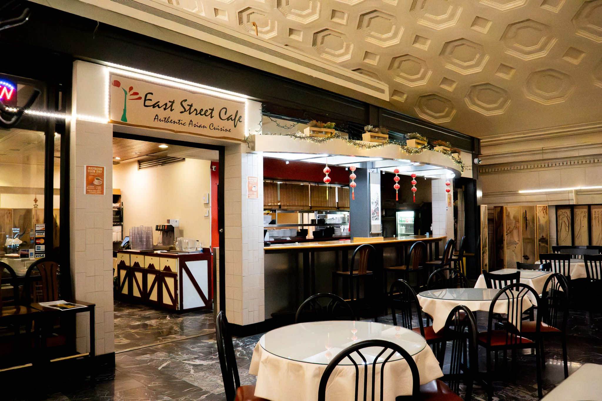 A logo featuring a stylized plant with red leaves on a vibrant yellow background, accompanied by the text 'East St. Cafe' and a tagline describing a culinary journey.