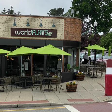Image of worldFLATS Ridgewood exterior with tables, chairs and umbrellas