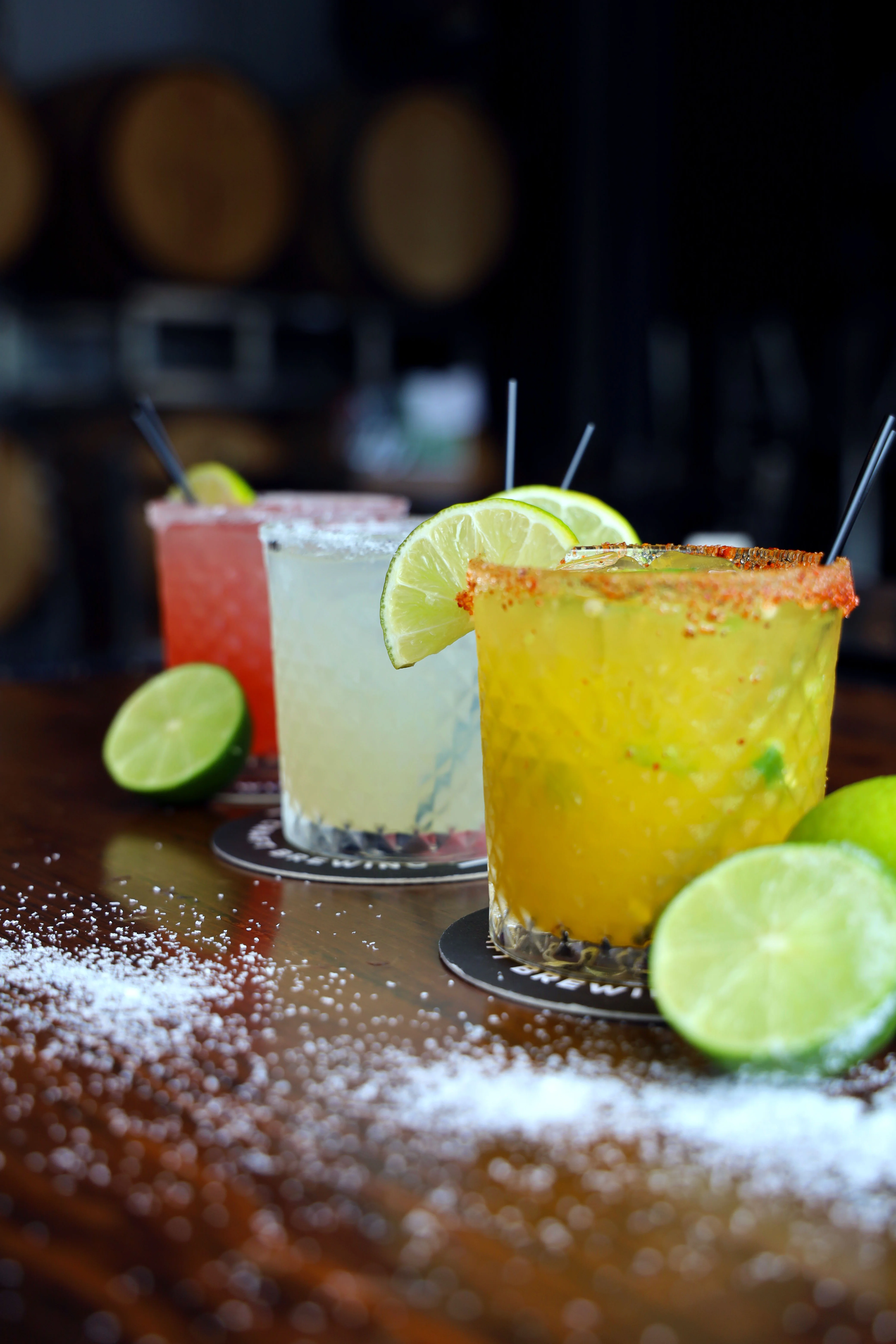 Three colorful cocktails on a table, showcasing vibrant garnishes.