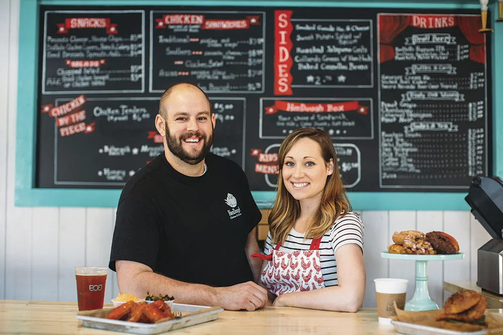 Cheerful restaurant owners in front of a menu board