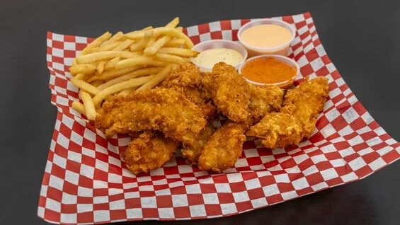 Crispy chicken tenders with fries and dipping sauces on a checkered tray