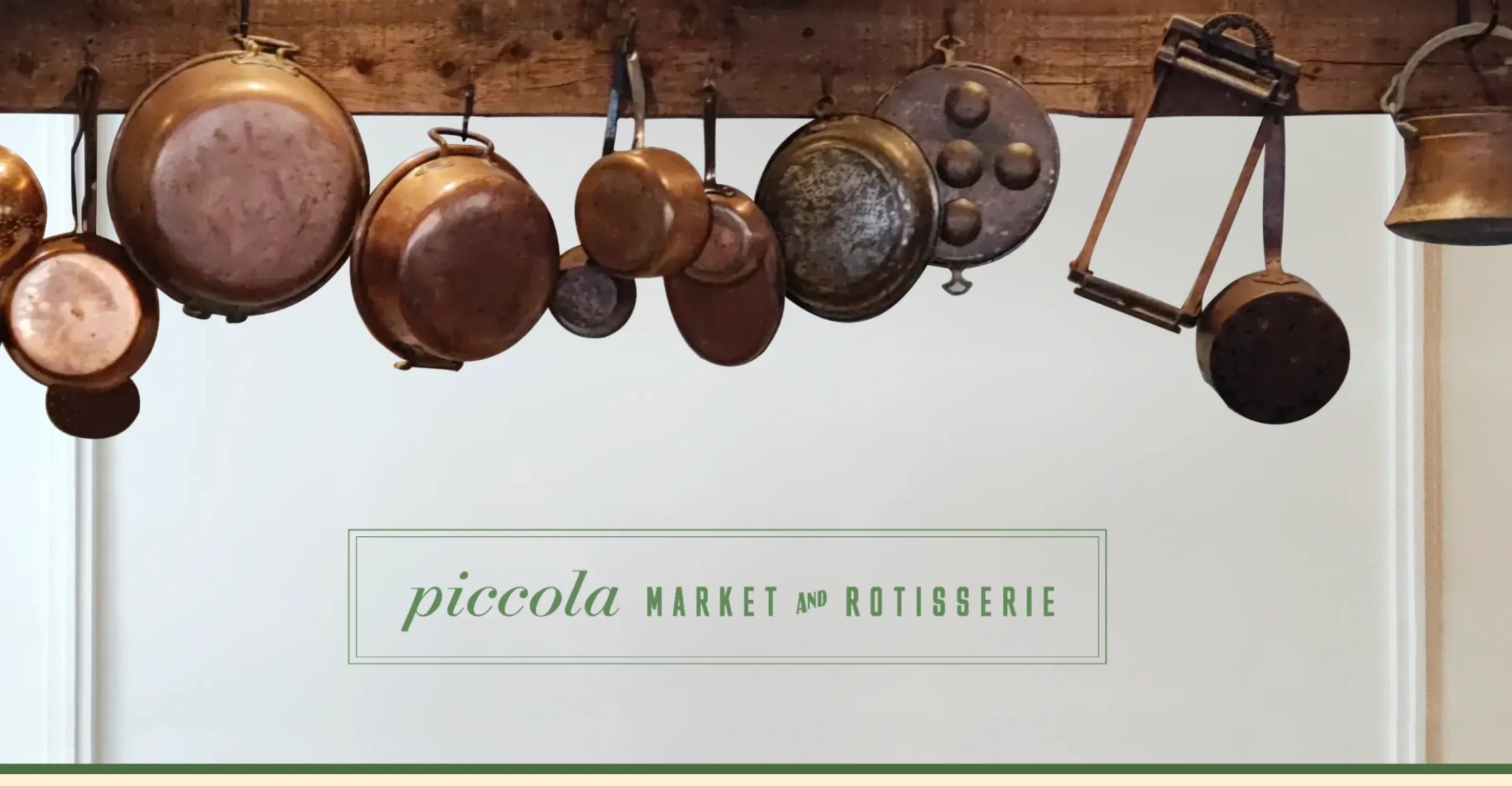 A collection of hanging copper and metal cookware suspended from a wooden beam, featuring various pots, pans, and a kitchen utensil.