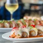 Colorful sushi rolls with garnishes served on a white plate