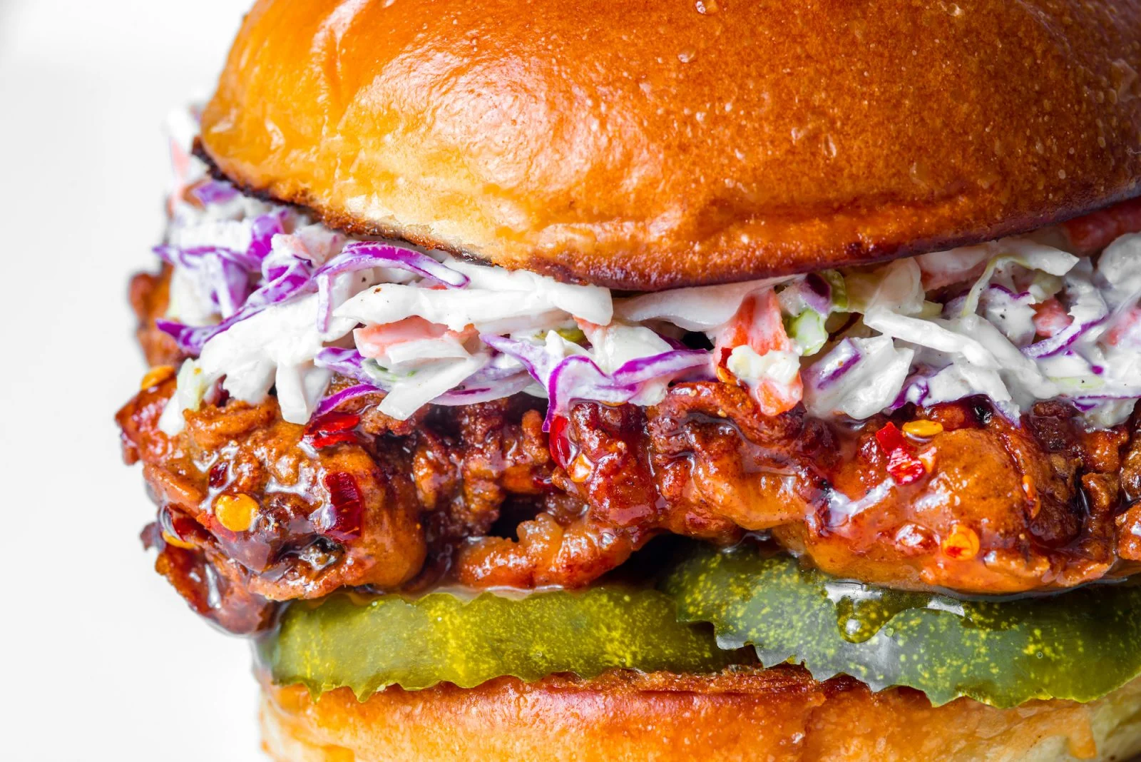 Delicious Hot Honey Chicken Sandwich with toppings on a wooden table.