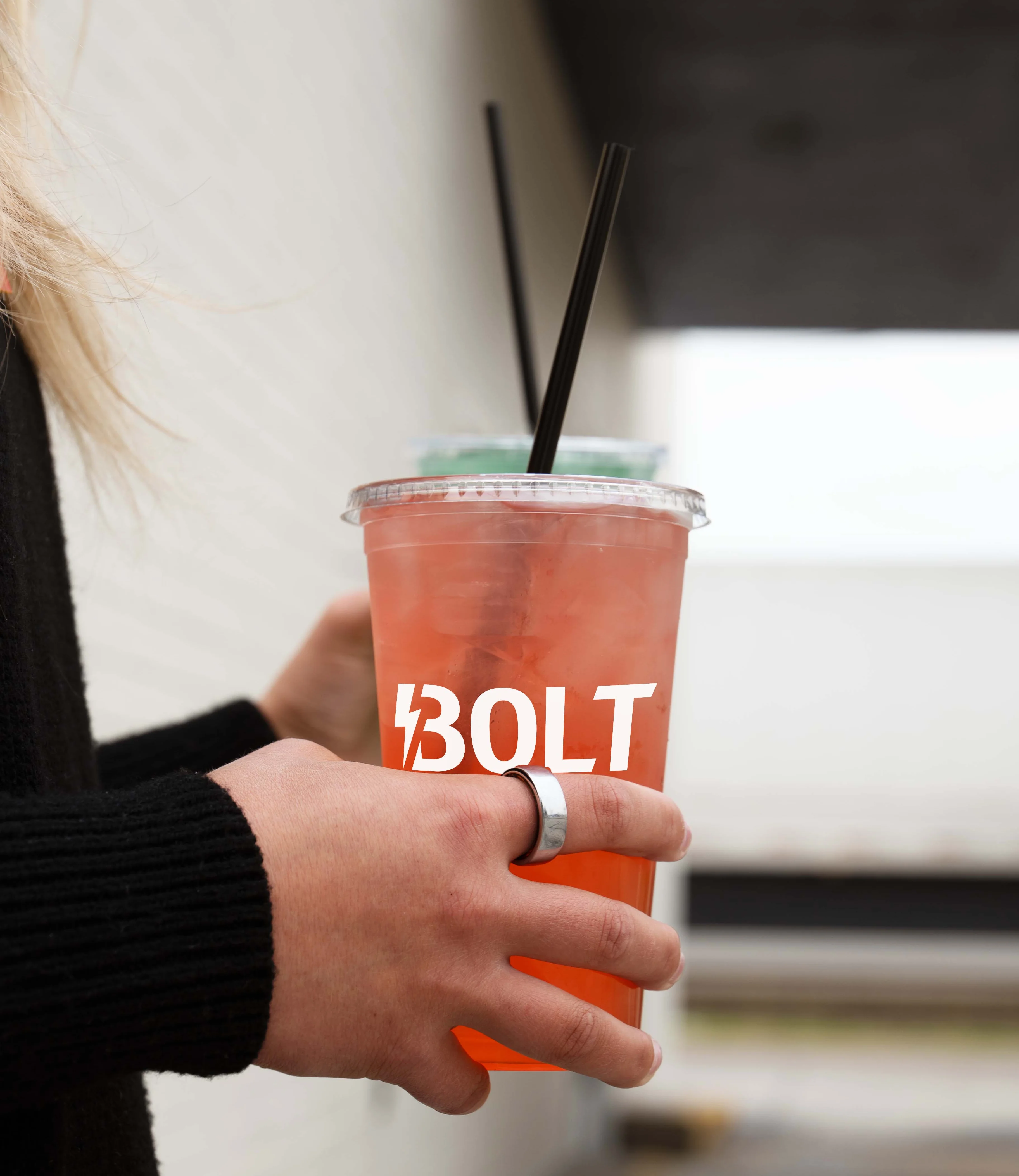 Person holding a drink with BOLT logo and two straws.