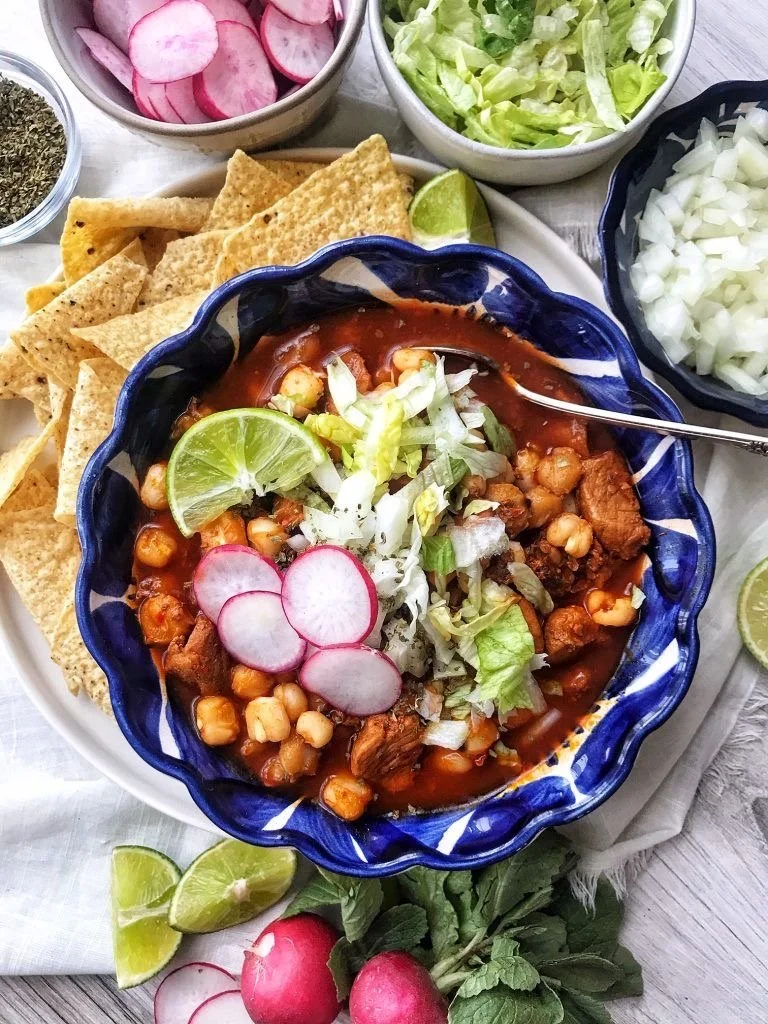 Bowl of Mexican posole topped with fresh garnishes