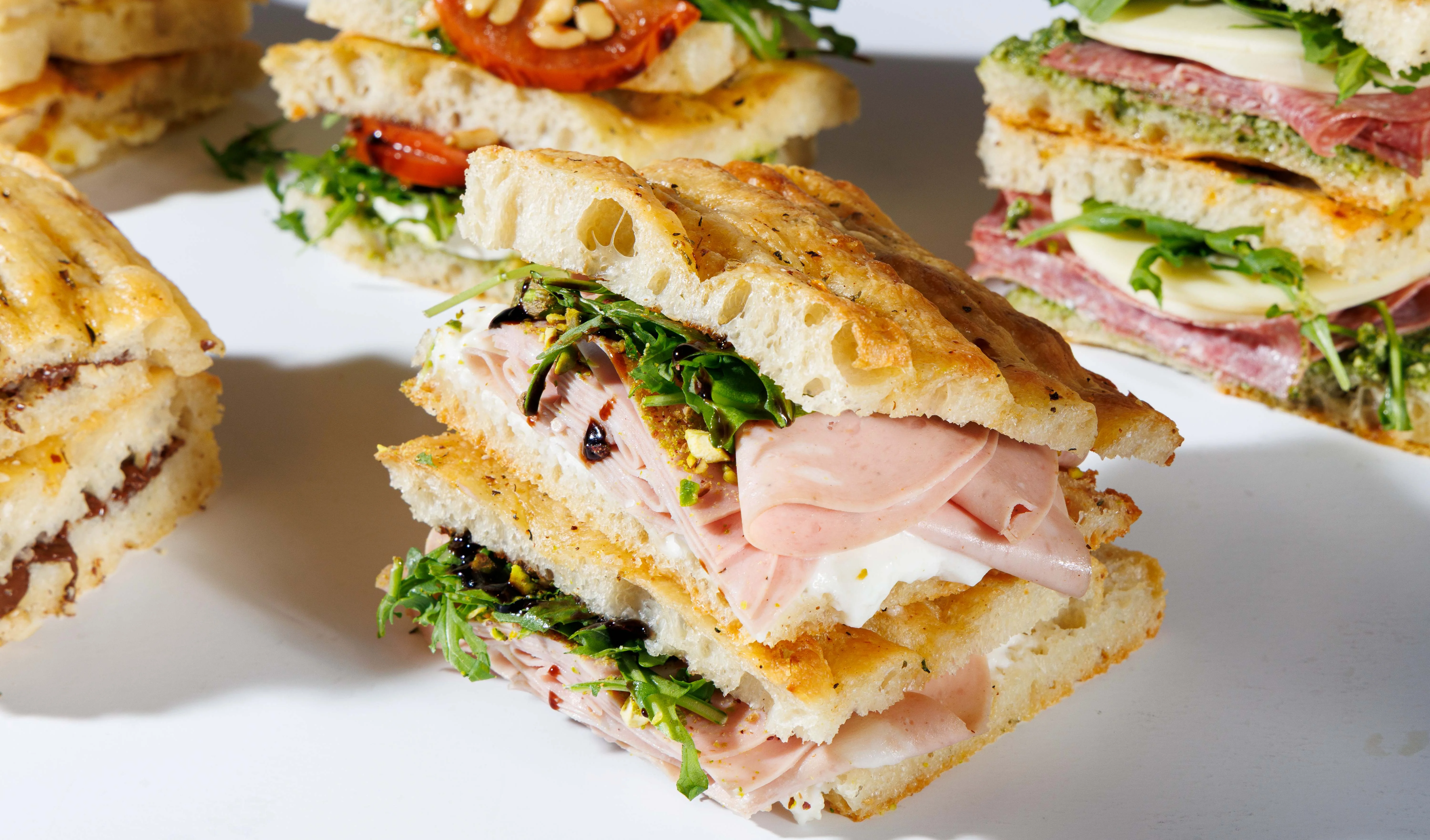Italian panini sandwich stacked with meats and greens