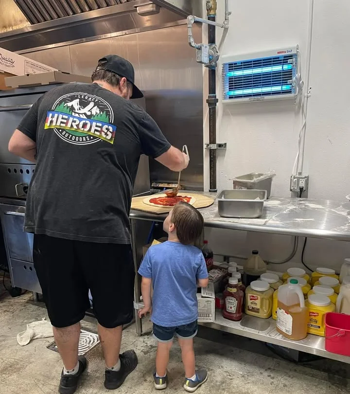 Child watching pizza being made in a restaurant kitchen